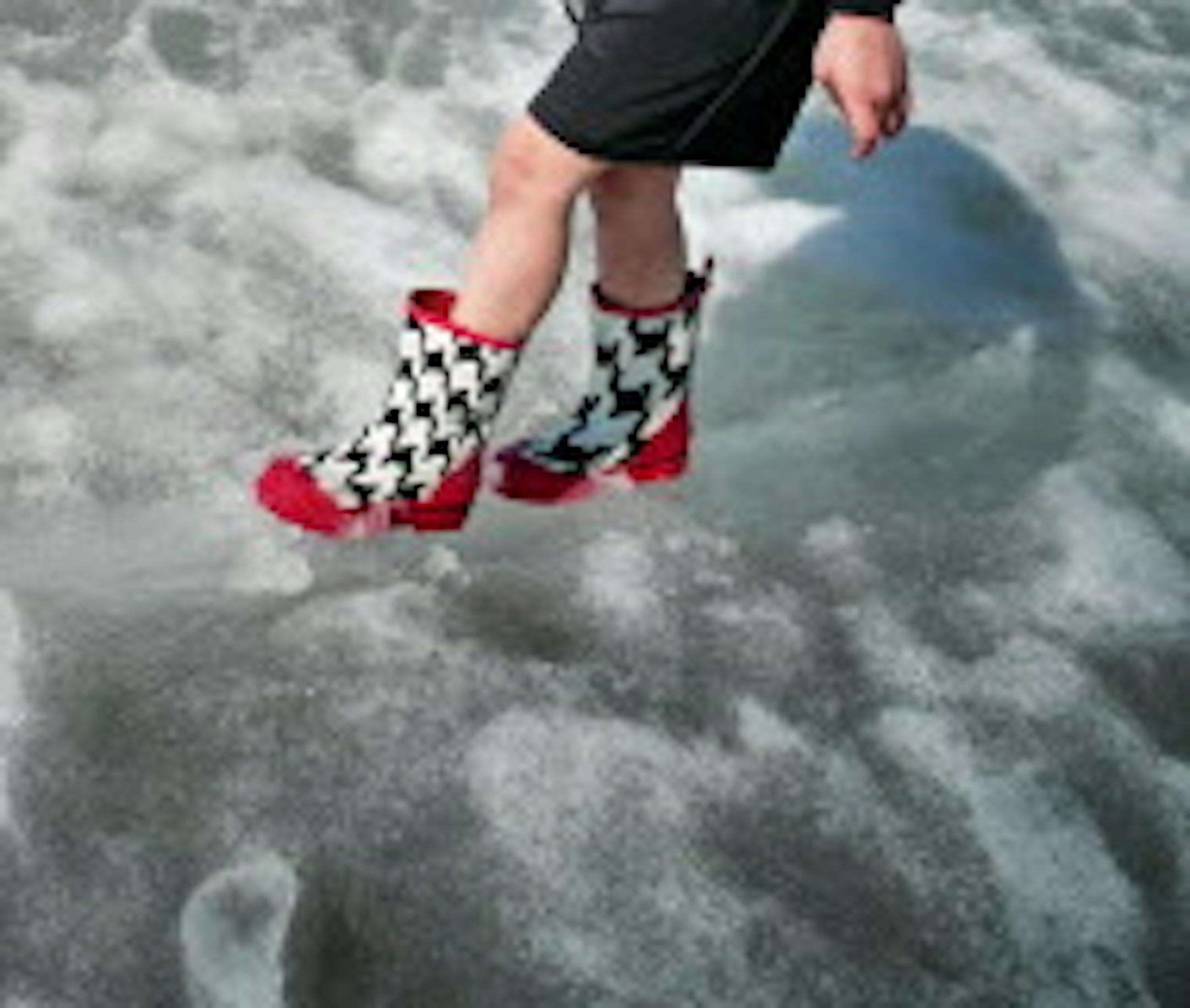 Gideon Frohlich, 7, was literally testing the slushy ice along the shoreline of Lake Calhoun, also known as Bde Maka Ska, in Minneapolis. He is home schooled part time and was enjoying the warm weather with his three siblings and his mother Angelina. (Richard Tsong-Taatarii/Star Tribune via AP)