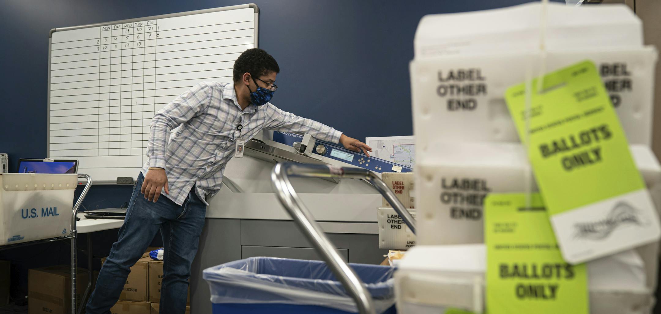 Elections administrator Jon Martin runs ballots through a machine that opens them and stamps the date they were received at Minneapolis Elections and Voter Services in July.