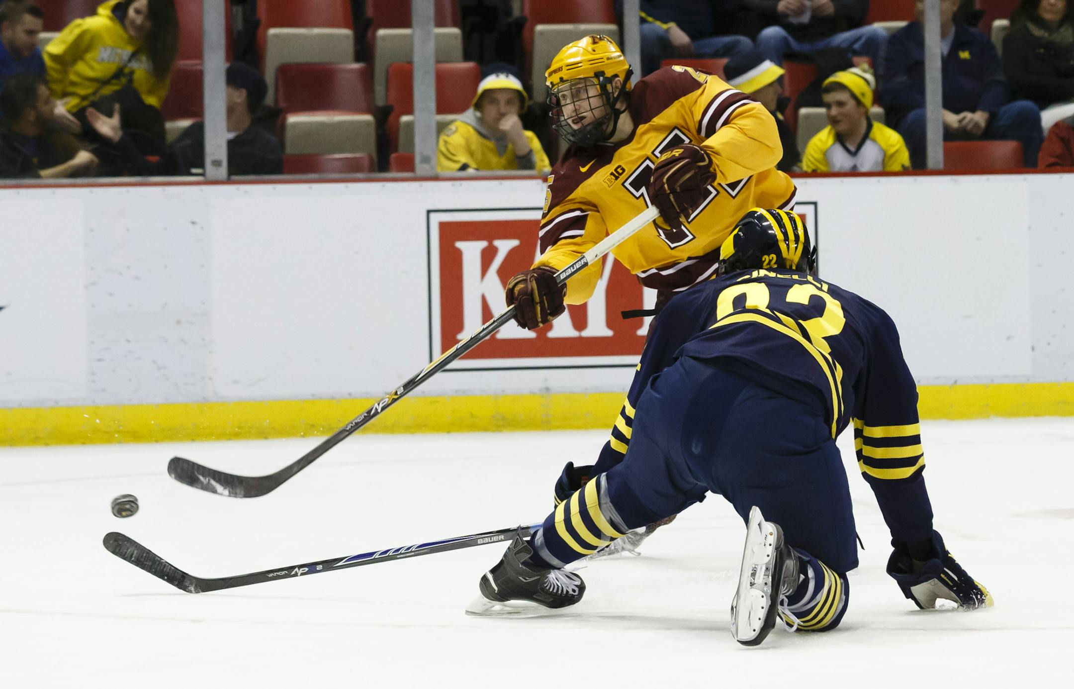 Minnesota's Justin Kloos (25) takes a shot defended by Michigan's Andrew Sinelli (22) in the first period during an NCAA college hockey game in the Big Ten Conference tournament Saturday, March 21, 2015, in Detroit. (AP Photo/Rick Osentoski)