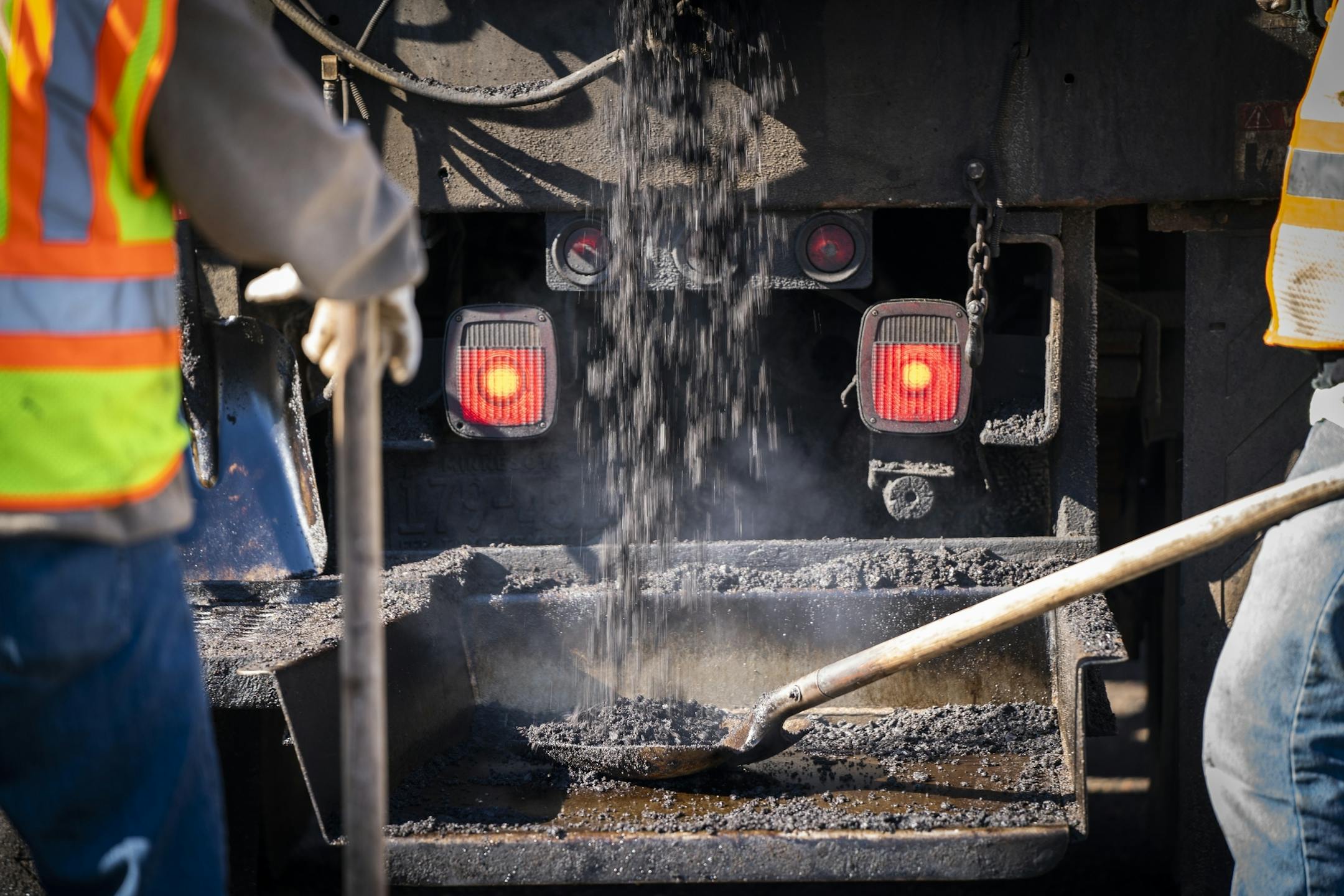 St. Paul Public Works street service workers load fresh asphalt onto shovels while patching potholes on Shepard Road.