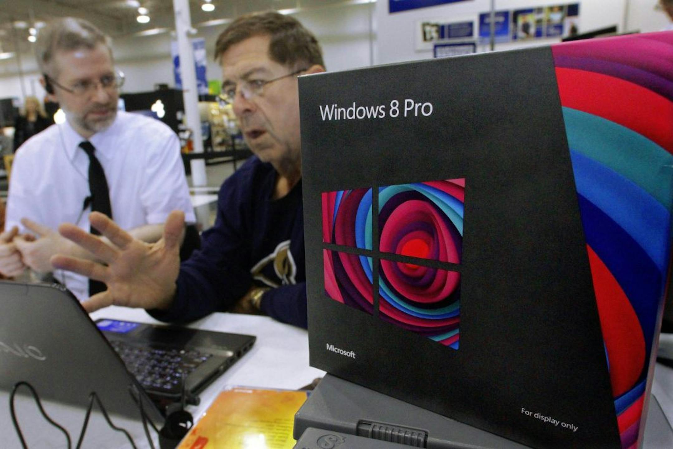 A Best Buy Microsoft Windows 8 consultant, David Smith, left, works with a customer, Pete Levan, right, demonstrating the features of the new Windows operating system during a media availability at Best Buy Friday, Oct. 26, 2012 in Springfield, Ill. Friday was the first day of sales for the new Windows 8 operating system.