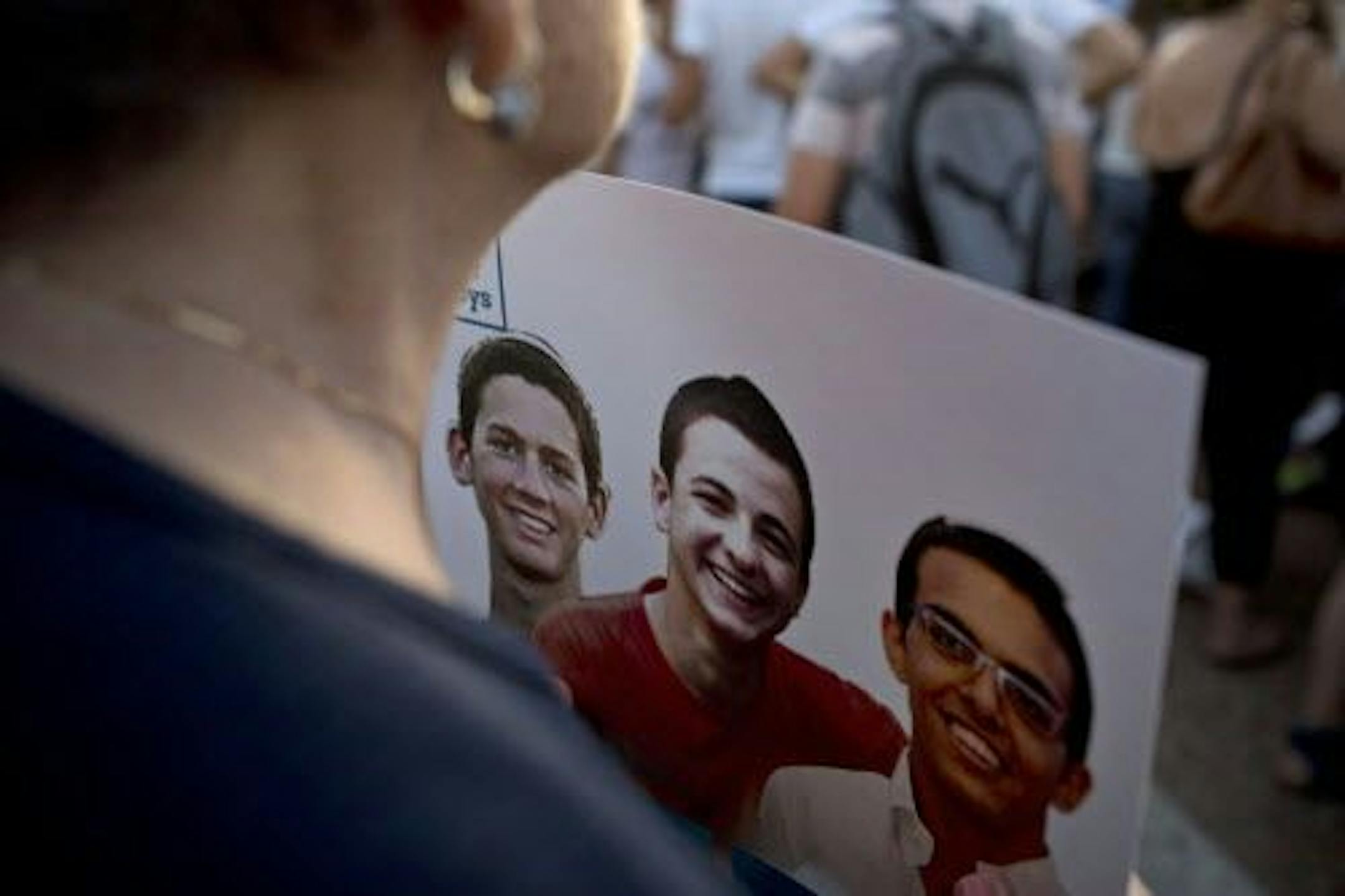 During a rally Sunday in Tel Aviv calling for the release of three abducted Israeli teens, a woman holds a poster with photos of the teens.