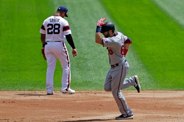 Minnesota Twins' Jake Cave, right, rounds the bases after hitting a grand slam as Chicago White Sox second baseman Leury Garcia looks down during the 