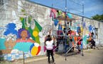 Community members work together on a mural transforming the facade of Clipper Cuts barber shop on Broadway Avenue in north Minneapolis.