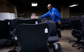 Aaron Mason, an employee at Furniture Office & Home, sorts office chairs from a new delivery into rows. The secondhand store in northeast Minneapolis