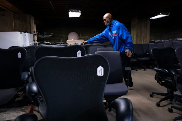 Aaron Mason, an employee at Furnish Office and Home, sorts office chairs from a new delivery into rows. The secondhand store in northeast Minneapolis 