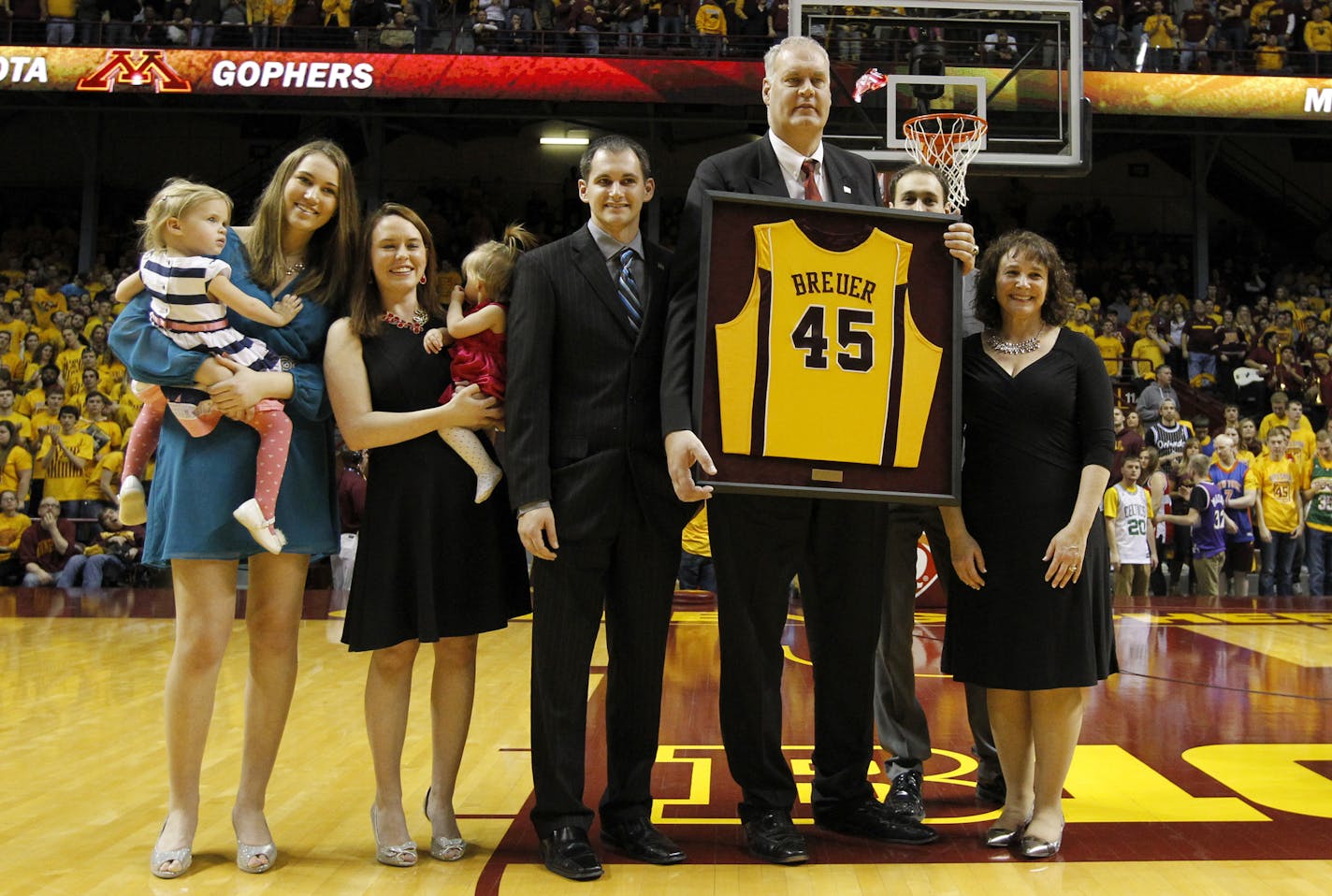 Former Minnesota and NBA player Randy Breuer is joined by his family during a ceremony to retire Breuer's jersey at half-time of an NCAA college basketball game against Illinois in Minneapolis, Saturday, Jan. 24, 2015. (AP Photo/Ann Heisenfelt)