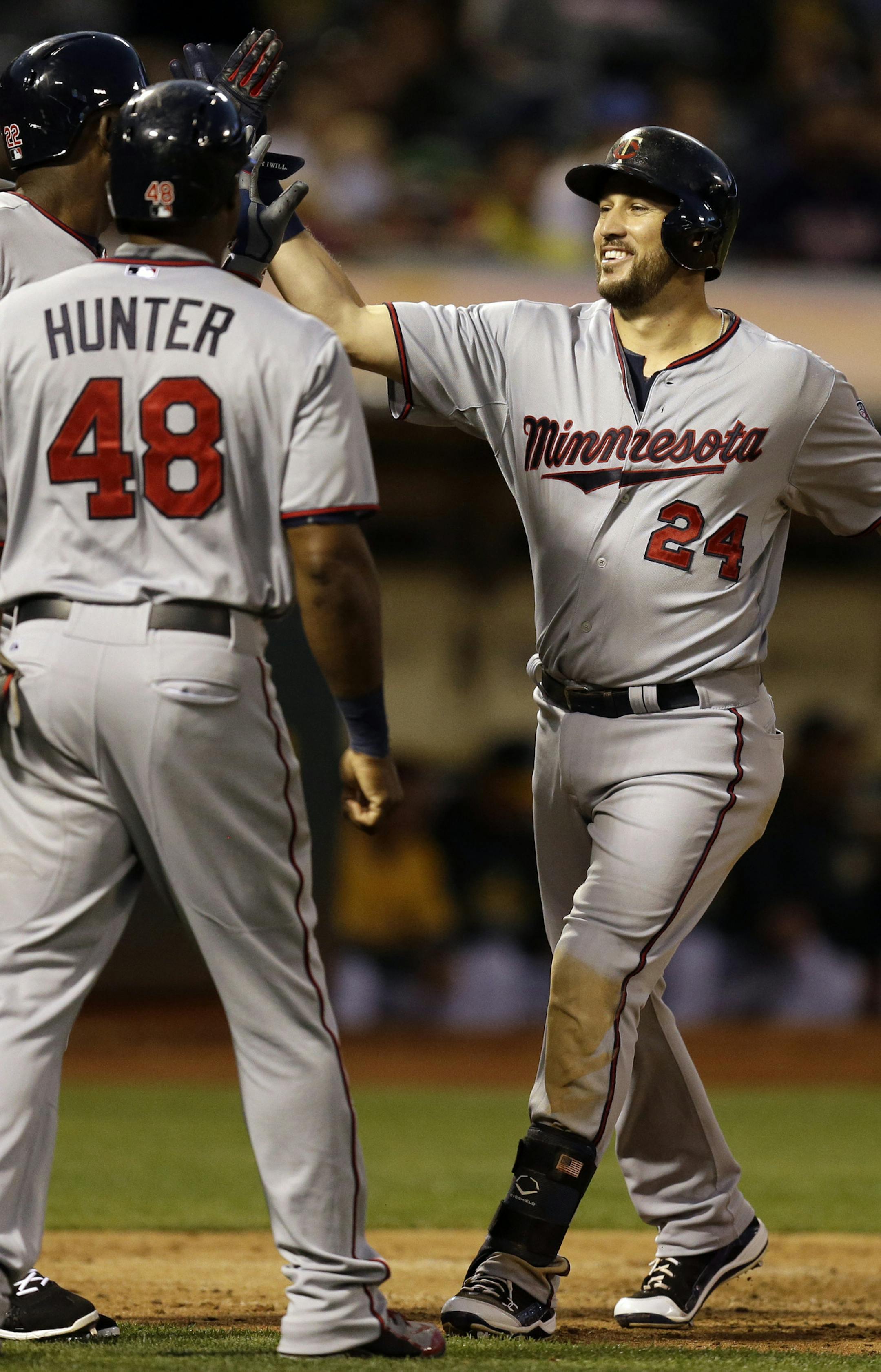 From left, Minnesota Twins' Brian Dozier, Miguel Sano, and Torii Hunter celebrate with Trevor Plouffe after Plouffe hit a grand slam off Oakland Athletics' Sonny Gray in the sixth inning of a baseball game Friday, July 17, 2015, in Oakland, Calif. (AP Photo/Ben Margot)