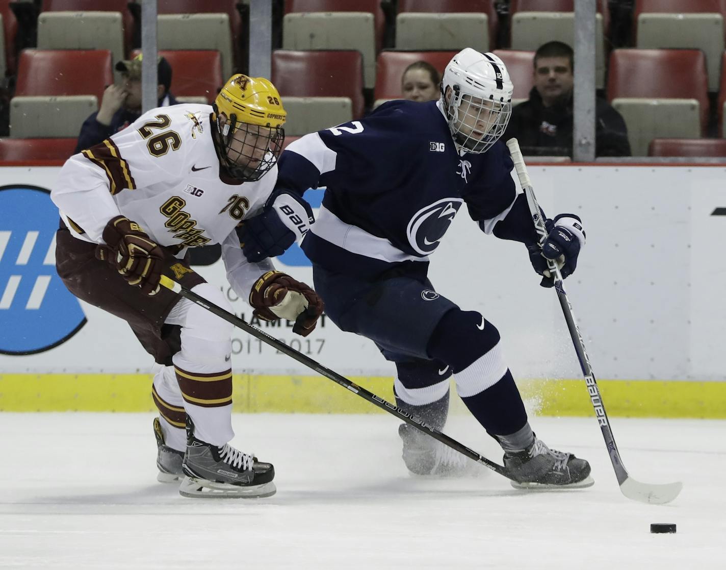 Minnesota forward Darian Romanko (26) and Penn State forward Dylan Richard (12) chase the puck during the first period of an NCAA college hockey semifinal match in the Big Ten Tournament, Friday, March 17, 2017, in Detroit. (AP Photo/Carlos Osorio)