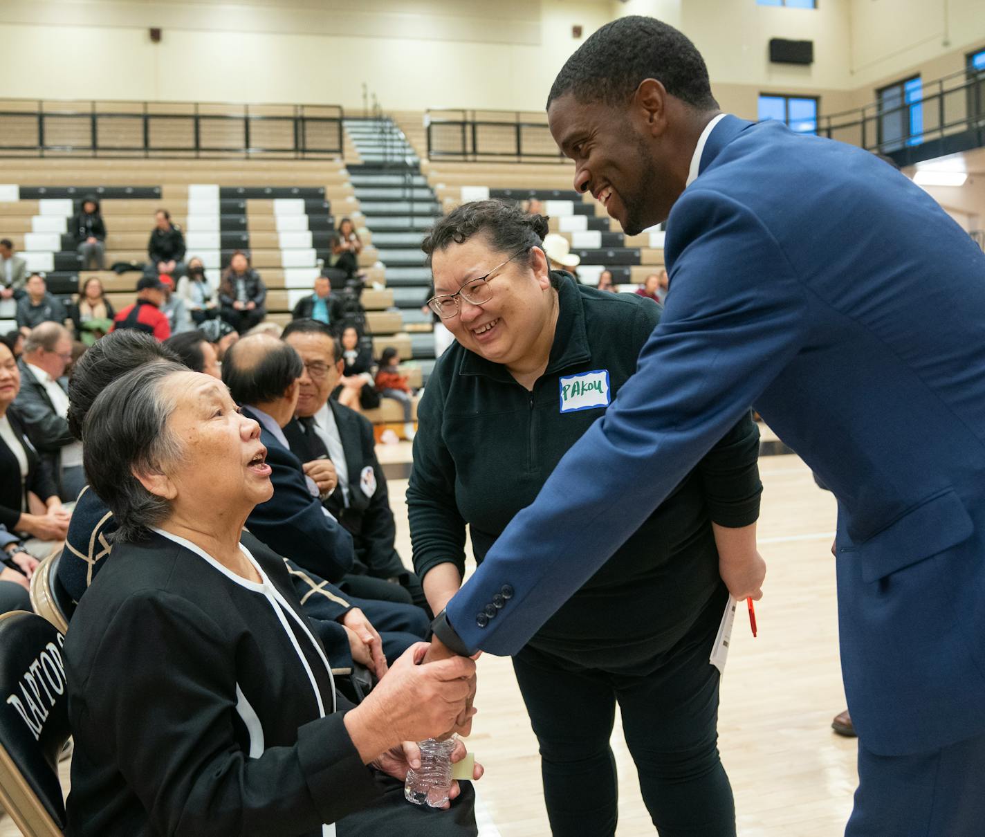 Sao Lou Vu, Tou Ger Xiong's mother, greeted St. Paul Mayor Melvin Carter before a vigil to celebrate the life of her son Saturday, Dec. 23, 2023, at East Ridge High School in Woodbury, Minn. Xiong was an artist and activist in the Twin Cities and was found dead in Medellin, Colombia after he was kidnapped, held for ransom and then killed. ]