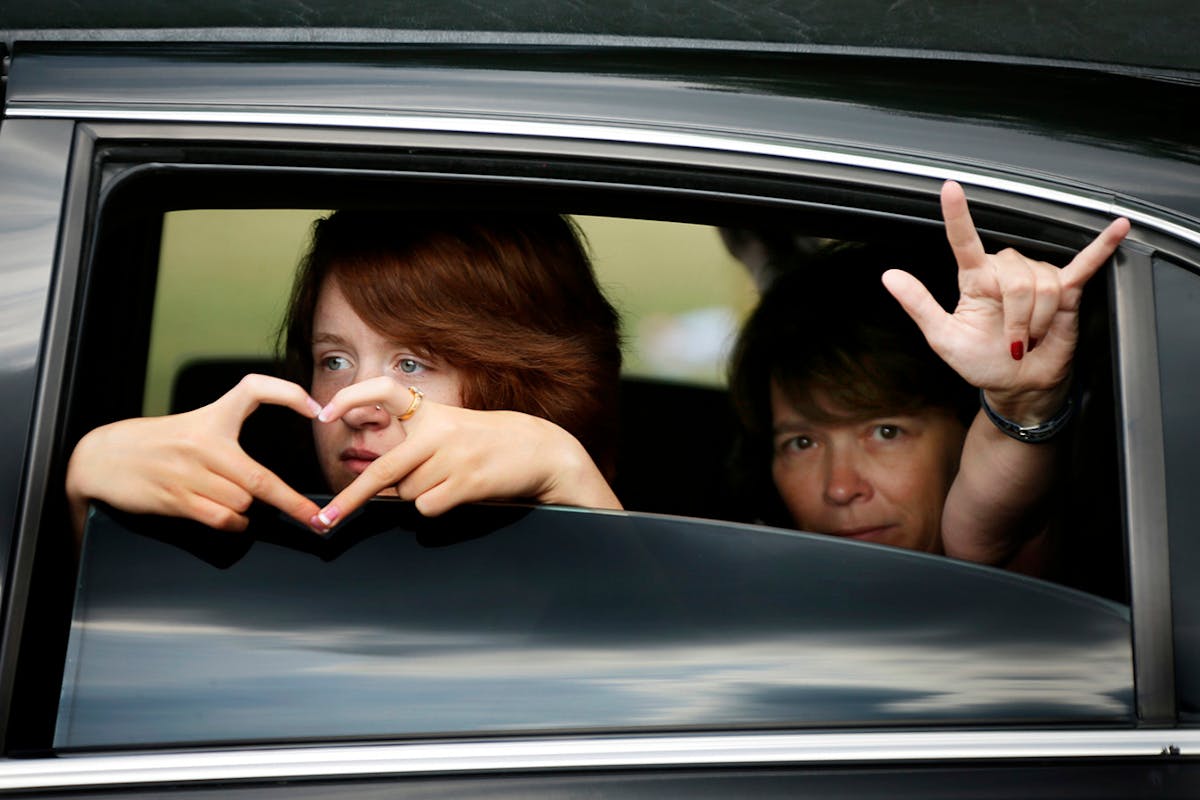 Scott Patrick's wife, Michelle, right, and one of their daughters show signs of love to the crowd as they entered Acacia Park Cemetery on Wednesday, A