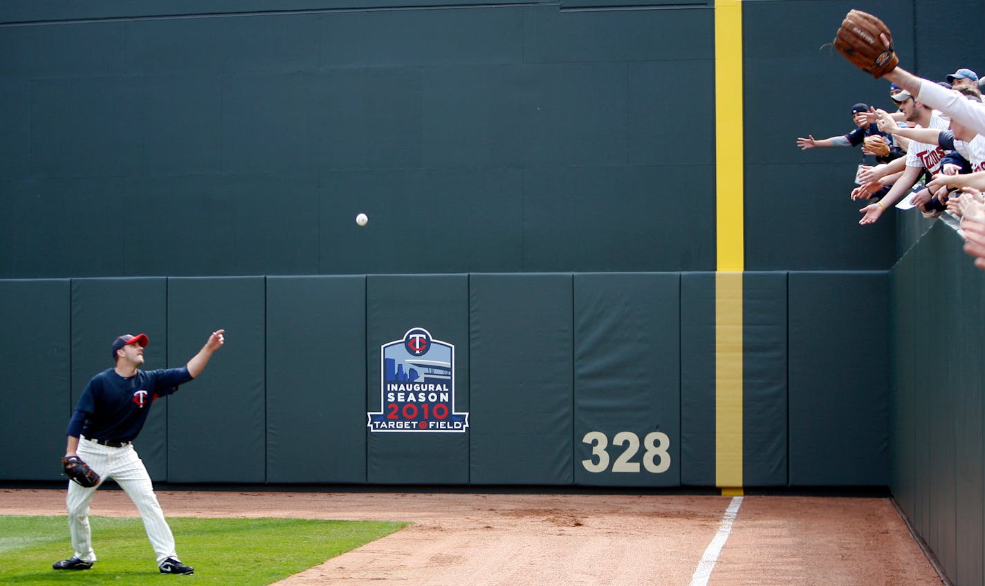 File photo: Fans reach for a ball thrown by Brian Duensing as they watched batting practice at Target Field.