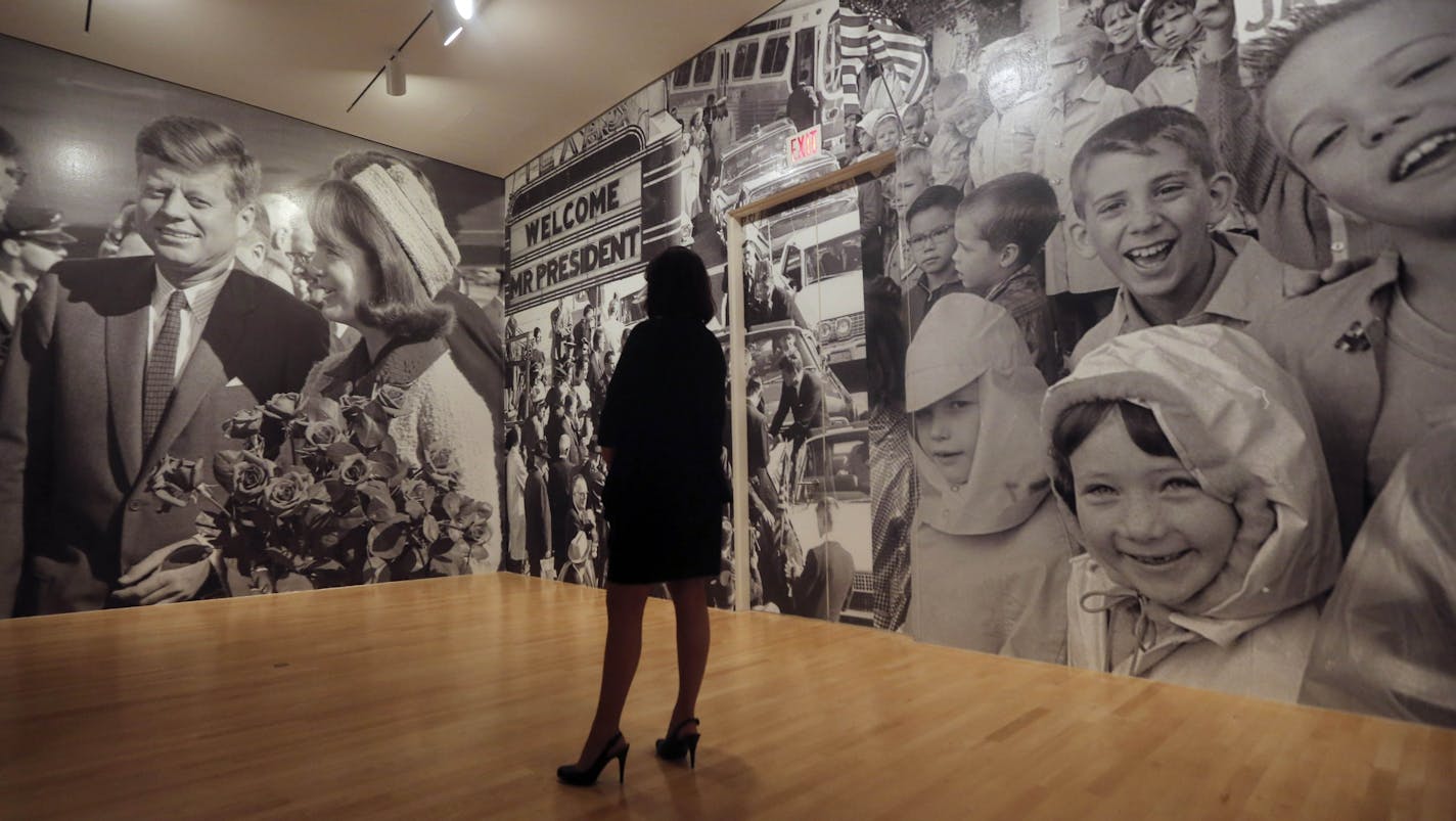 FILE - In this Wednesday, May 22, 2013 file photo, a woman looks a mural of photos in the exhibit "Hotel Texas: An Art Exhibition for the President and Mrs. John F. Kennedy" during a preview at the Dallas Museum of Art. The assassination of John F. Kennedy was the event that first defined the Baby Boomer generation that has defined the way we look at the world 50 years later.