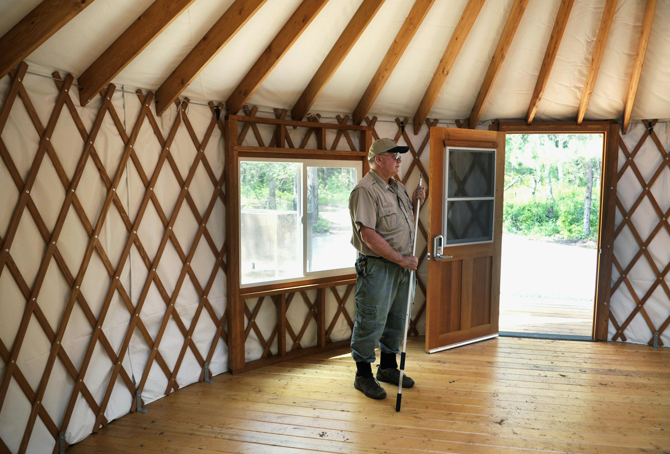 In this photo taken on July 29, 2014, Cuyuna Country State Recreation Area manager Steve Weber holds a pole used to raise or lower the ceiling hatch in one of three yurts under construction at the SRAís Yawkey Unit, just north of Crosby, Minn. Four screened windows plus a screen in the door will catch the breeze. Woodstoves will make the structures habitable year-round. (AP Photo/St. Cloud Times, William Camargo) ORG XMIT: MIN2014081613570726