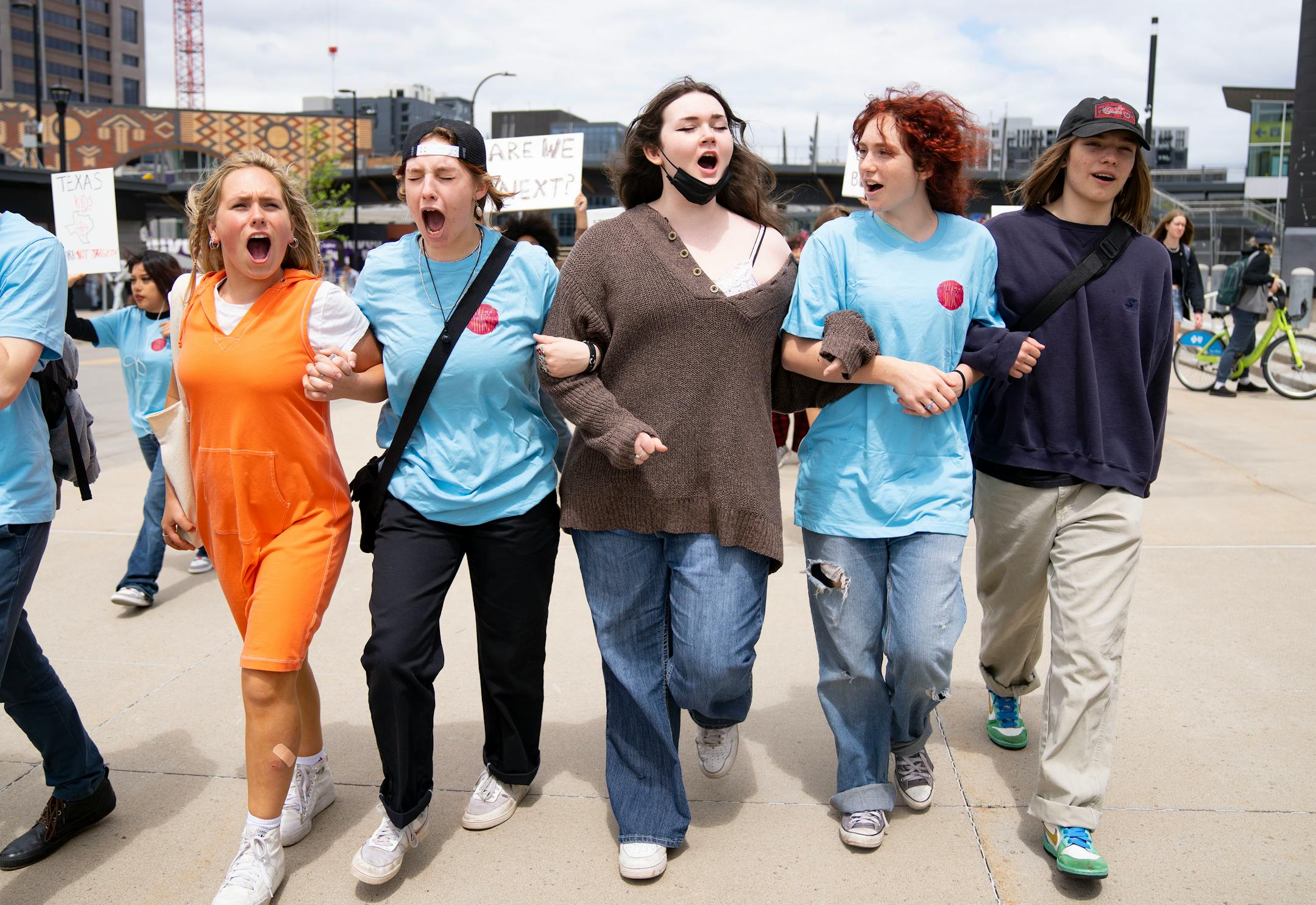 A group of students link arms and chant as they march.
