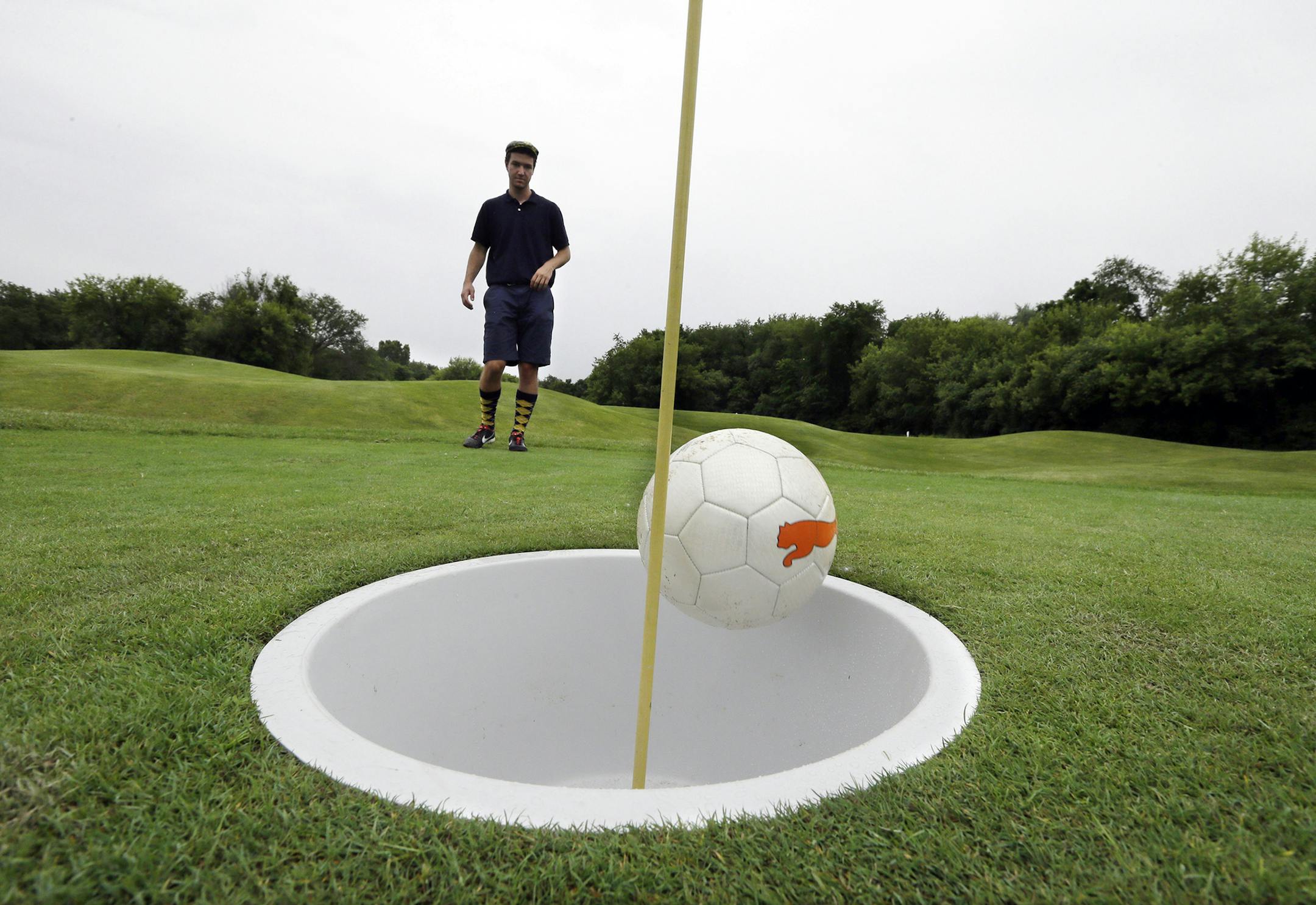 In a photo from June 20, 2014 in Salem Township, Mich., Brian Eggenberger putts his ball during a round of FootGolf at Fox Hills Golf Course. FootGolf, a soccer-golf hybrid is helping courses draw younger, more diverse customers. Players ‚Äútee off‚Äù _ minus the tees of course _ by kicking a soccer ball from the tee box. They follow the basic rules of golf from there, advancing the ball until it drops into the oversized hole. (AP Photo/Carlos Osorio) ORG XMIT:
