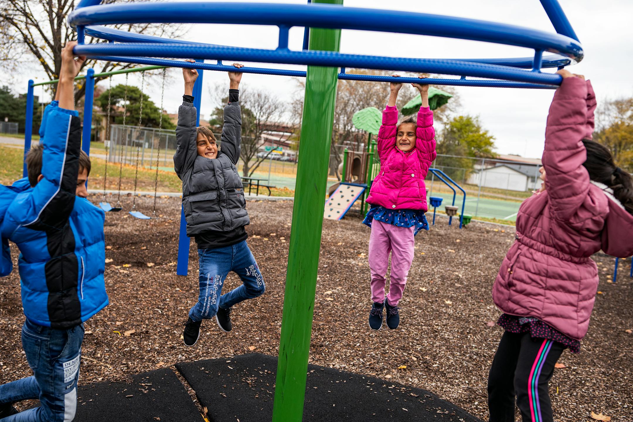 Mirwais Momand's children play with Maryam Mulakhail, 5, far right, on a playground in Bloomington.