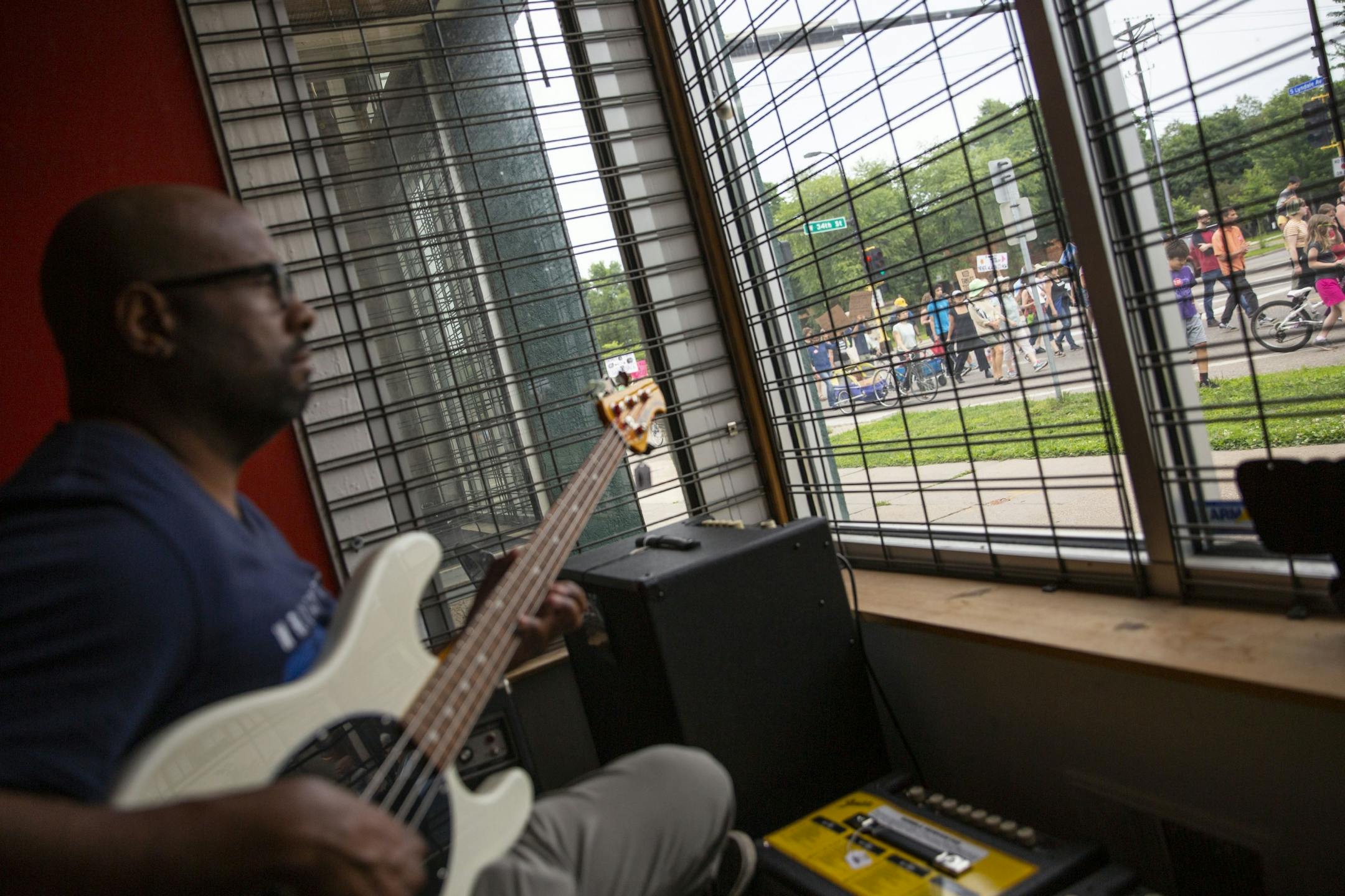 Deric Jackson practices guitar in a music store as he watches the march move through the streets. ALEX KORMANN ¥ alex.kormann@startribune.com Approximately 1,000 people marched through the streets of Minneapolis on Sunday June 30, 2019 protesting the treatment of migrants on the U.S. border. "Stop separating families, close the camps," said Mari Mansfield, an organizer for the event.