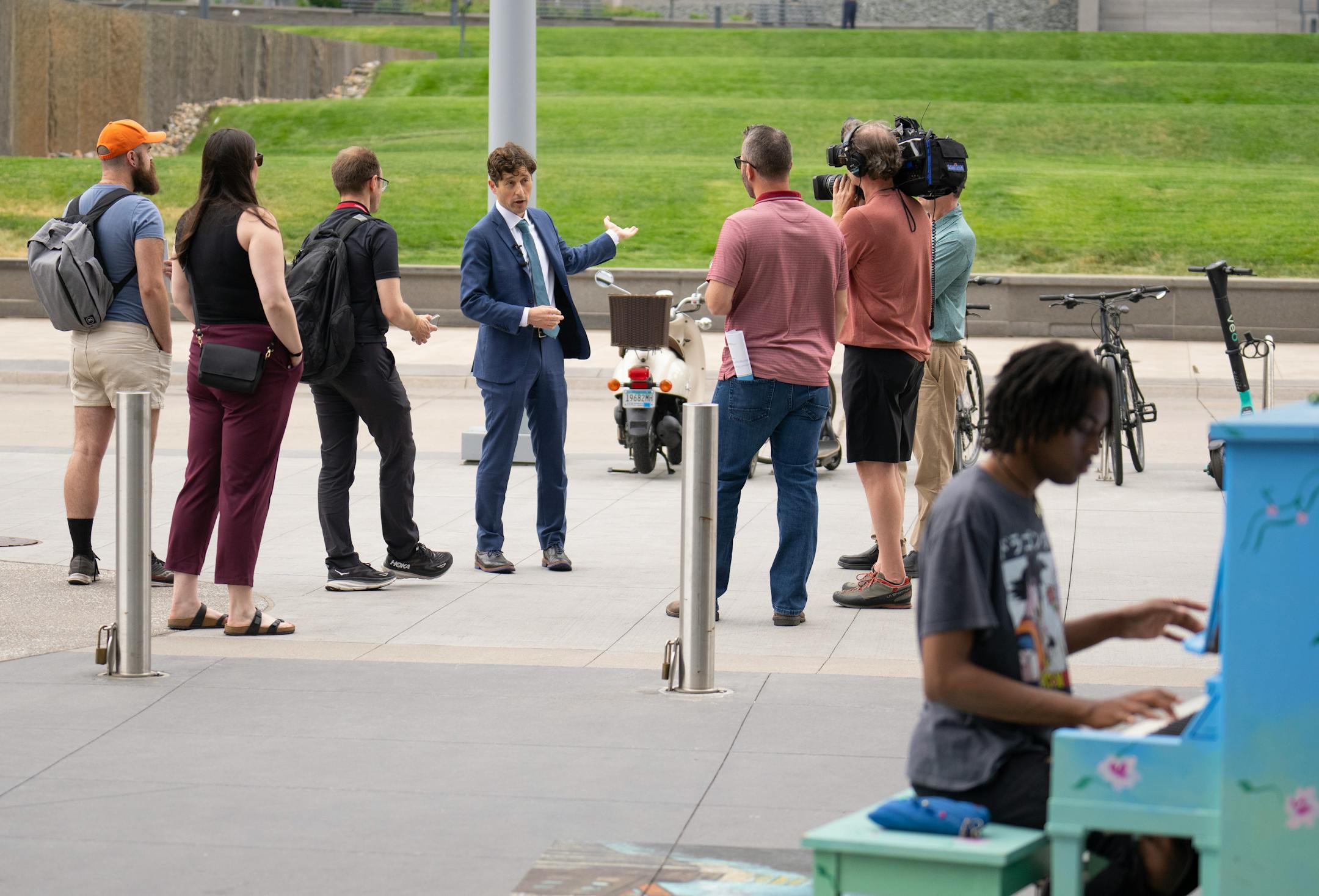 Minneapolis Mayor Jacob Frey led local media on a walking tour of a stretch of the Nicollet Mall that could see changes such becoming pedestrian-only. In the foreground, Tyrell Lee worked on a composition on an outdoor piano. Before that he was joined at a news conference Tuesday, June 6, 2023 at Dayton's by members of his newly formed "Vibrant Downtown Storefronts Workgroup" to announce recommendations the group submitted to him.