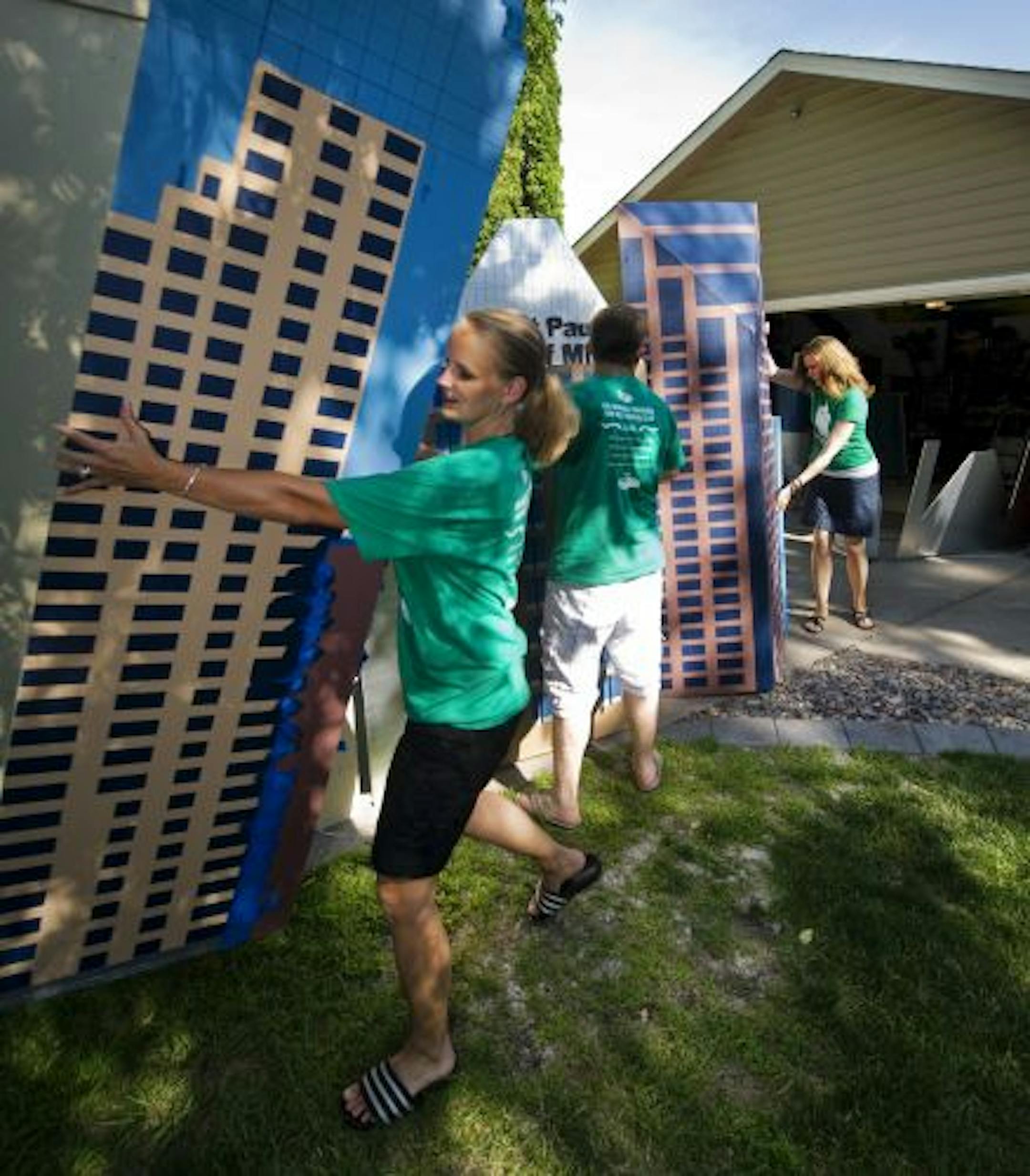 Clockwise, from left: Shari Gibson (front), Matt Gibson and Shodee Sawyer moved pieces of their entry, which is based on the St. Paul skyline. Sawyer painted a piece while Gibson helped. The team has been in three other flugtags but is competing in its hometown for the first time on Saturday.