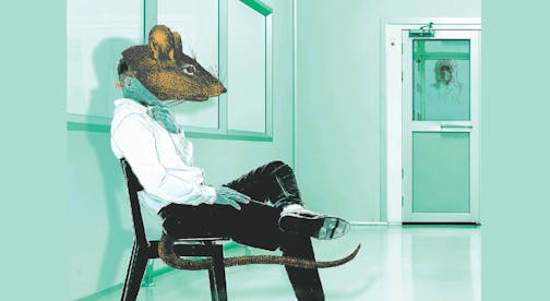 A man wearing a rat mask sits in a green waiting room