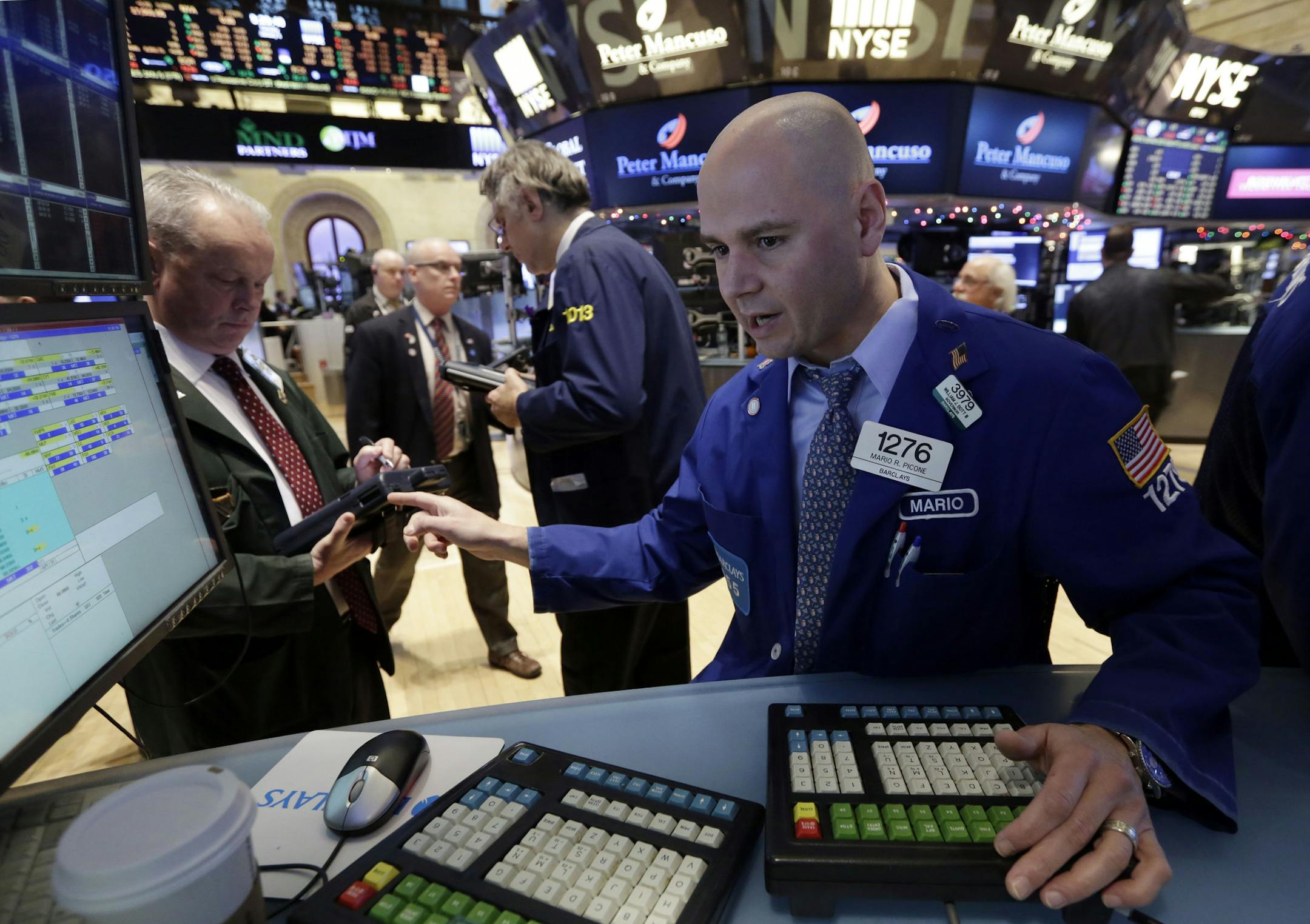 Specialist Mario Picone, right, works at his post on the floor of the New York Stock Exchange Tuesday, Jan. 6, 2015. The U.S. stock market is edging higher in early trading as the price of oil extends its slump. (AP Photo/Richard Drew)