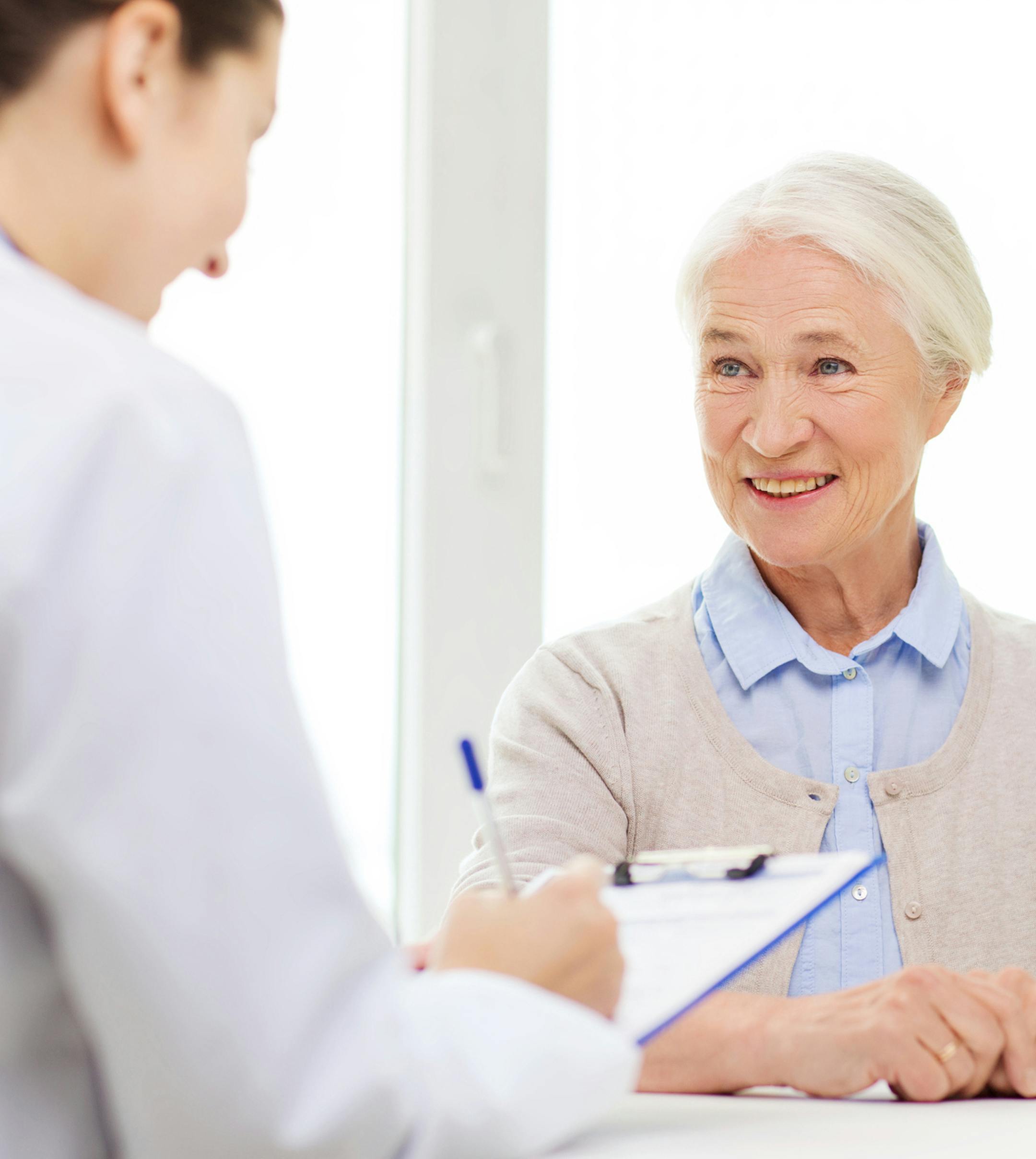 medicine, age, health care and people concept - doctor with clipboard writing prescription for senior woman at hospital. istock