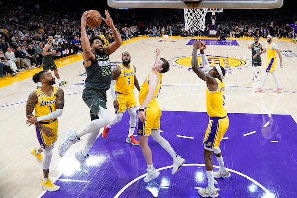 Minnesota Timberwolves forward Karl-Anthony Towns (32) shoots from between Los Angeles Lakers guard D'Angelo Russell (1), forward LeBron James (6), gu