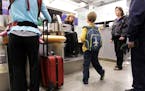 Judah Jore, 7, center, waits for his mother to obtain boarding passes at a Delta desk at Minneapolis-Saint Paul International Airport April 22, 2013. 