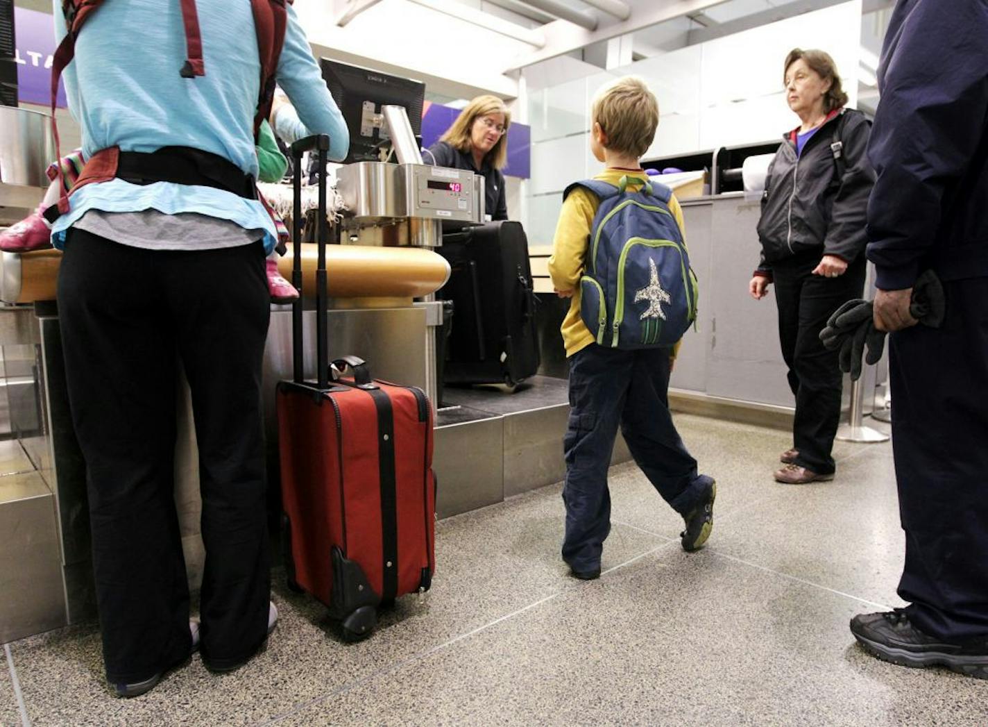 Judah Jore, 7, center, waits for his mother to obtain boarding passes at a Delta desk at Minneapolis-Saint Paul International Airport April 22, 2013. After visiting his grandmother Ellen Monseth, right, of Rogers, his family was traveling back home to Uganda. So far their flights were on time, and Judah's mother Rhoda Jore, left, was not concerned about potential future delays due to FFA budget cuts.