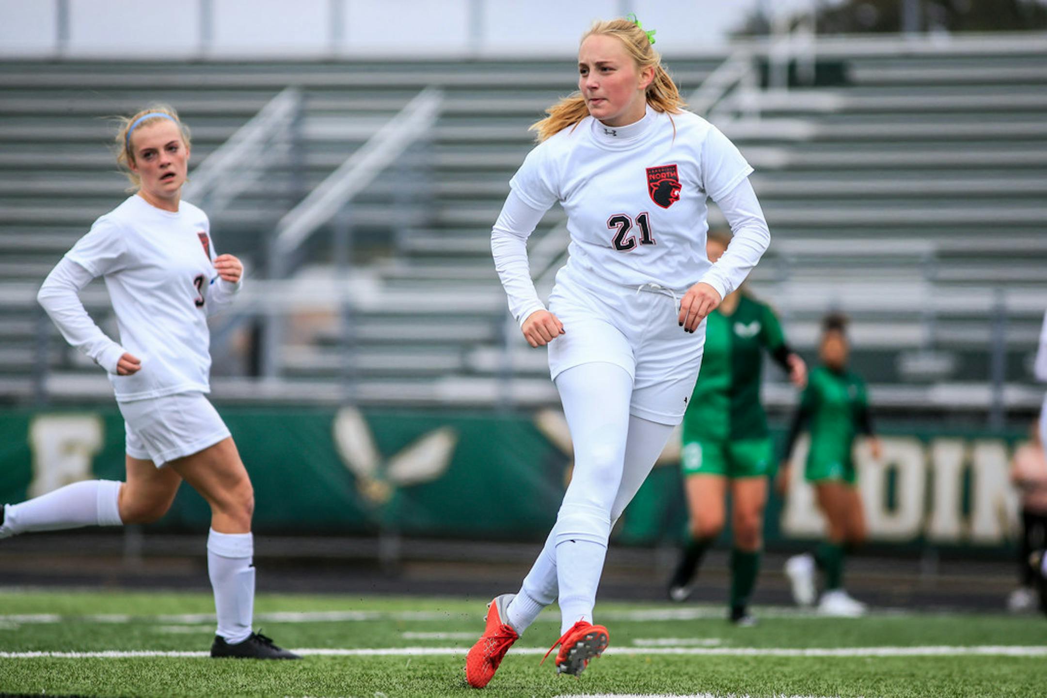Lakeville North's Sydney Gelhorn (21) on the field at Edina in a game on Oct. 6. Her teammates and often opponents as well wore green ribbons in their hair in support of Gelhorn after her father died in September. Photo: Mark Hvidsten, SportsEngine