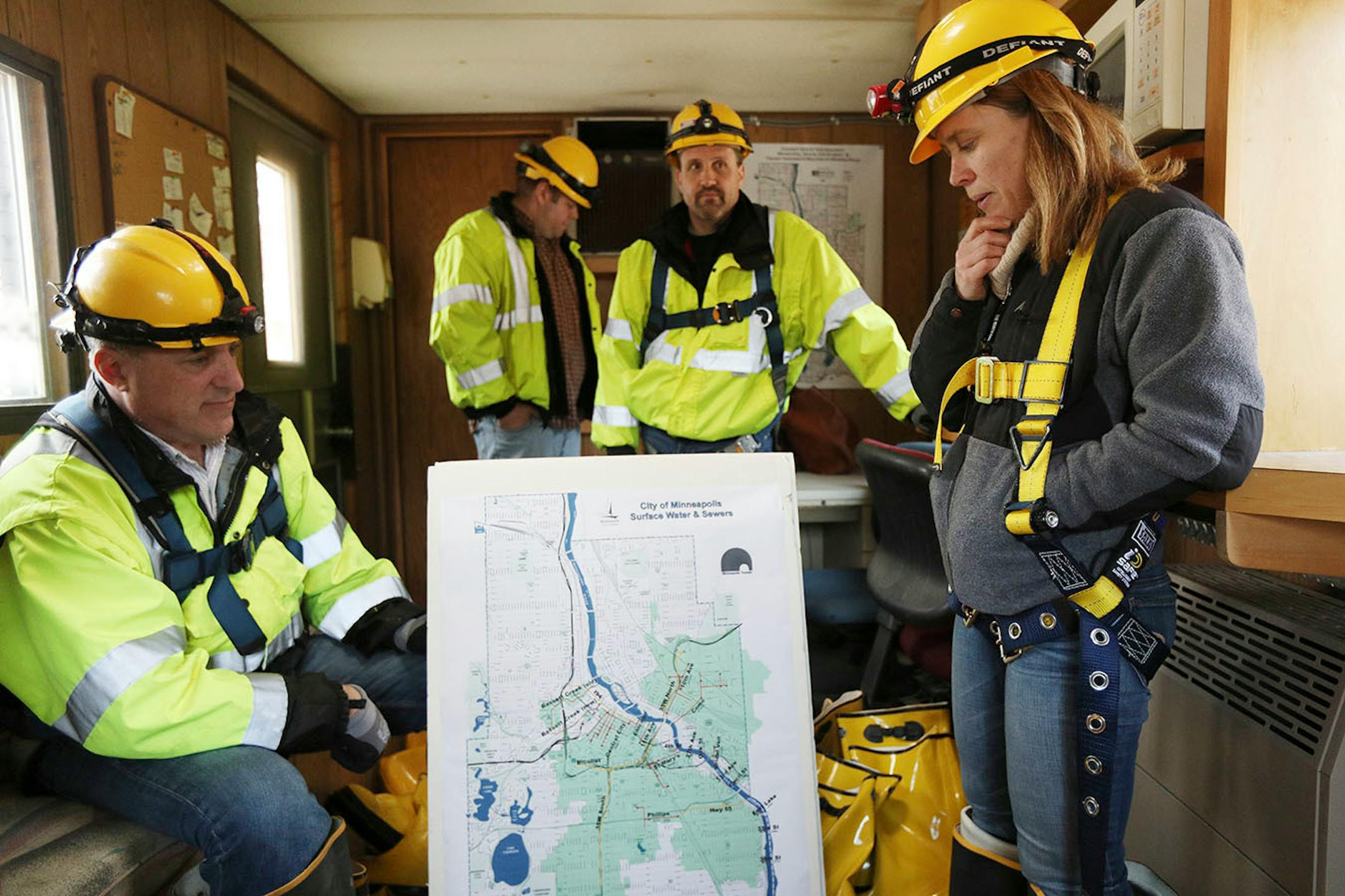 Katrina Kessler, director of Surface Water and Sewers for the Minneapolis Public Works Department, looked over a map of the city's storm sewers before leading a tour underground. At left is sewer engineer Joe Klejwa, at center is sewer operations engineer Kevin Danen.