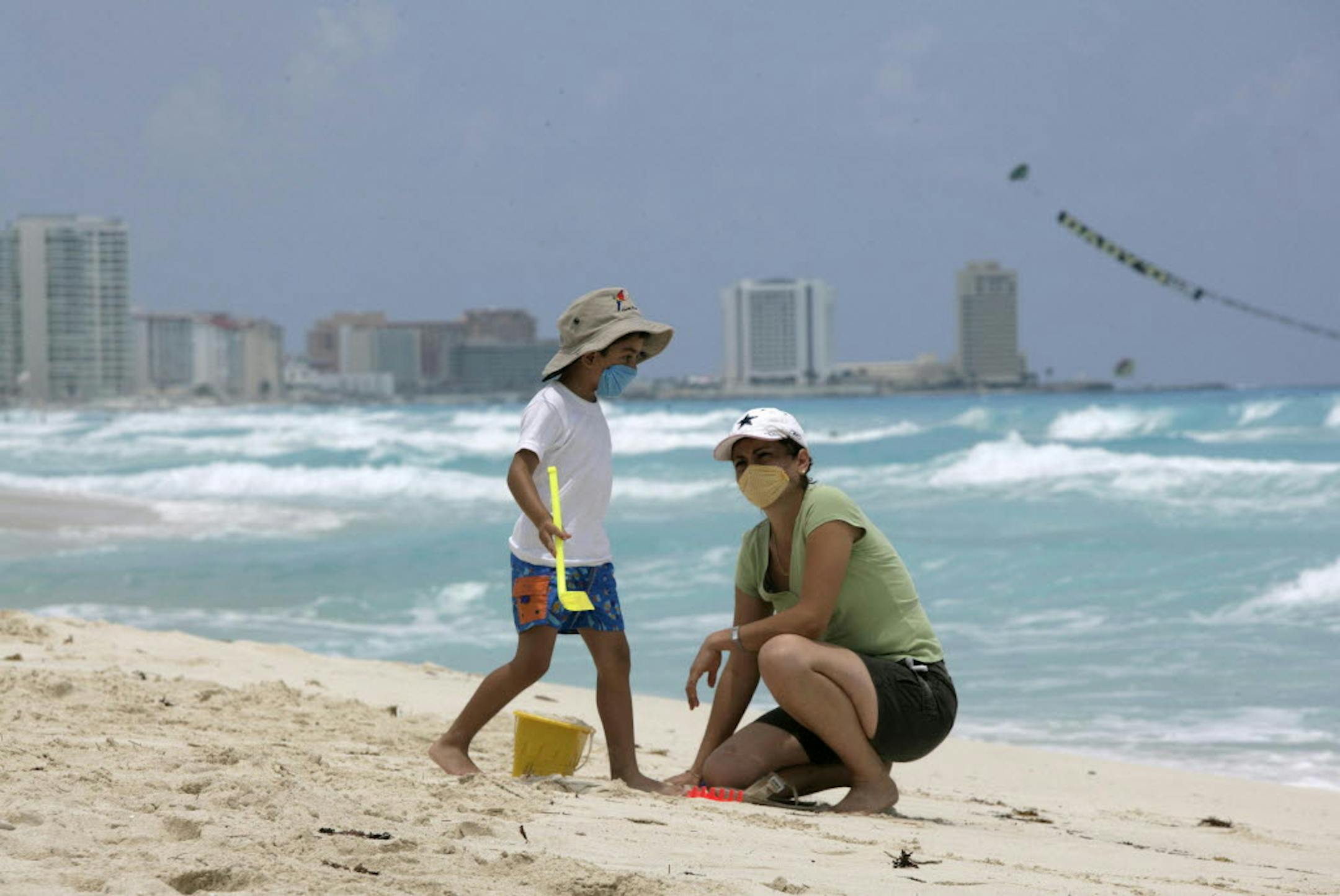 Wearing protective face masks as a precaution against swine flu contagion, a mother and child realx at a beach in Cancun, Mexico, Thursday. While Mexico fights to contain a swine flu outbreak, the tourism industry is hurting nationwide.