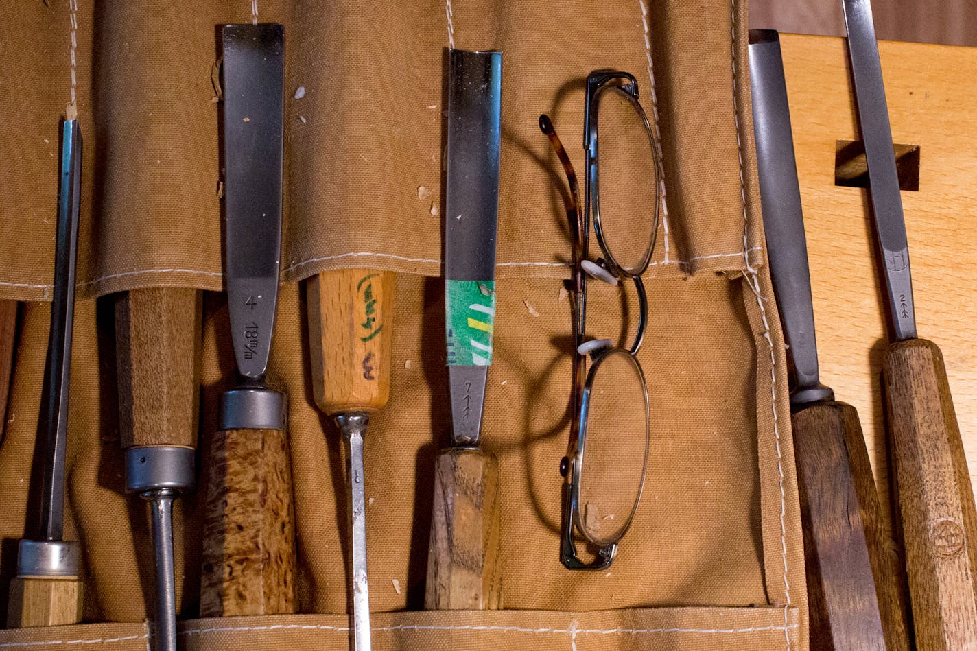 Jock Holmen's glasses next to his chisels in the classroom at his home in Burnsville.