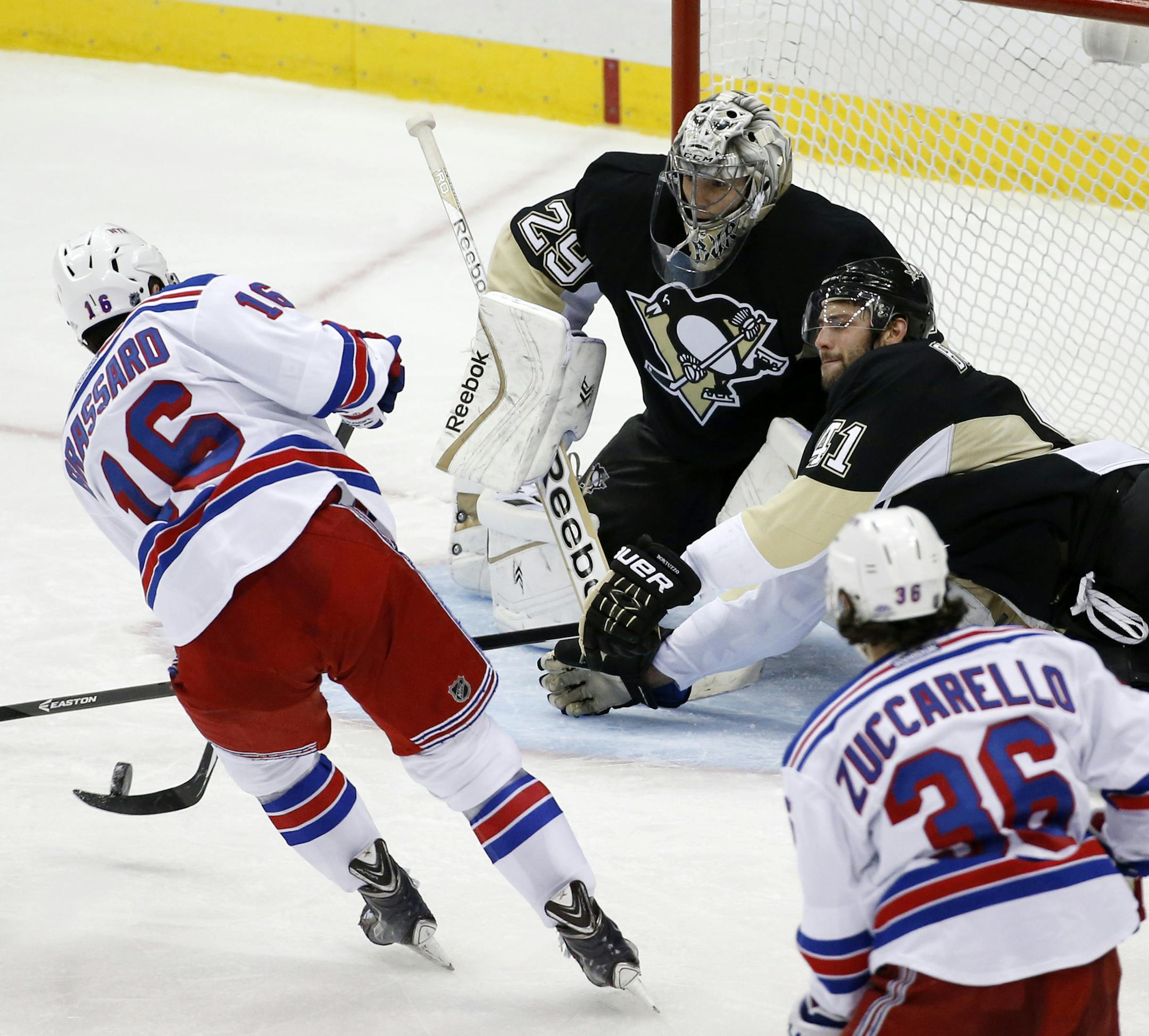 New York Rangers' Derick Brassard (16) puts the puck past Pittsburgh Penguins goalie Marc-Andre Fleury (29) and Robert Bortuzzo (41) for the game-winning goal in the first overtime period of Game 1 of a second-round NHL hockey playoff series in Pittsburgh, Friday, May 2, 2014. The Rangers won 3-2. (AP Photo/Gene J. Puskar)