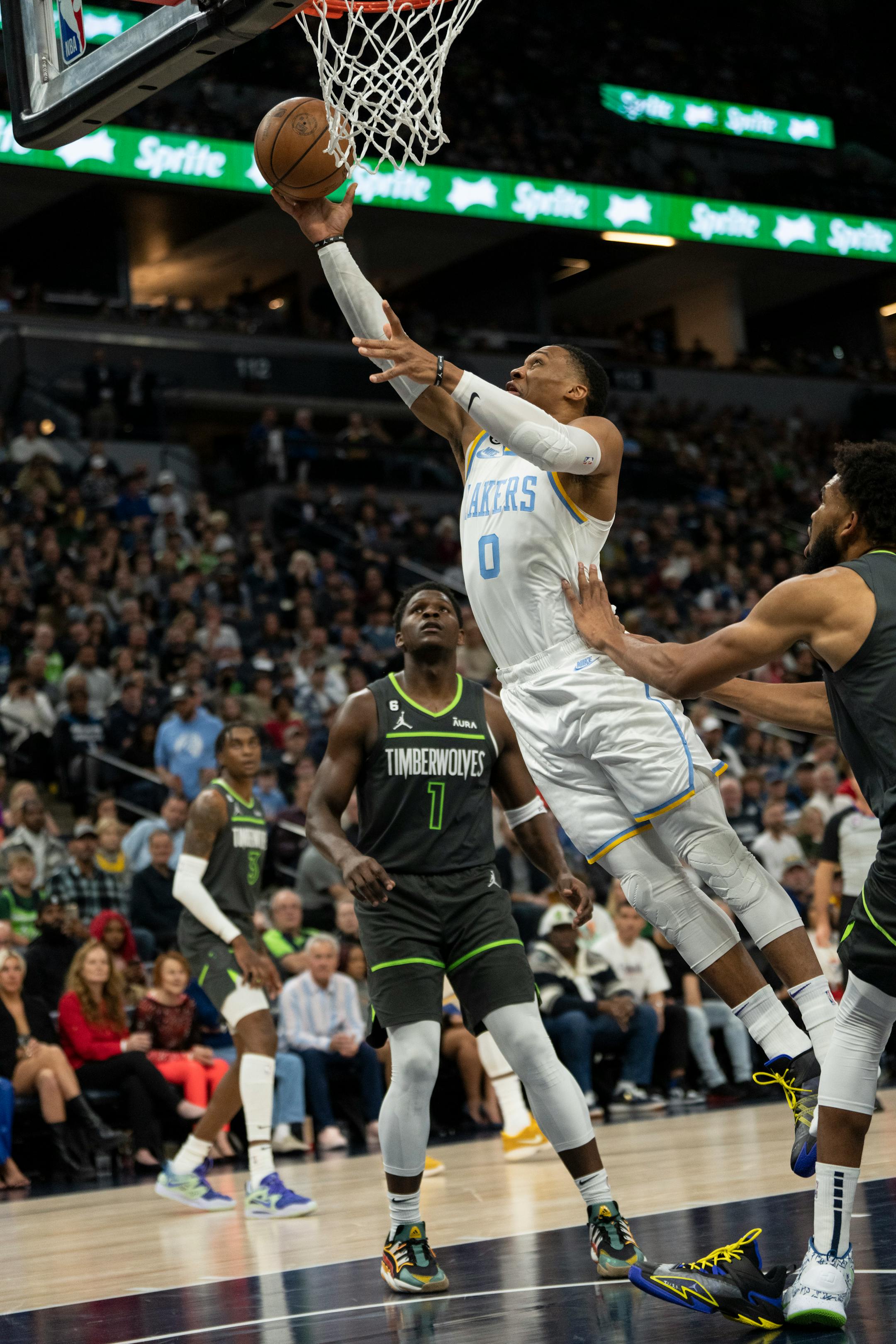 Minnesota Timberwolves center Karl-Anthony Towns (32) stands on Los Angeles Lakers guard Russell Westbrook's (0) shoe pulling it off during his layup in the first quarter.