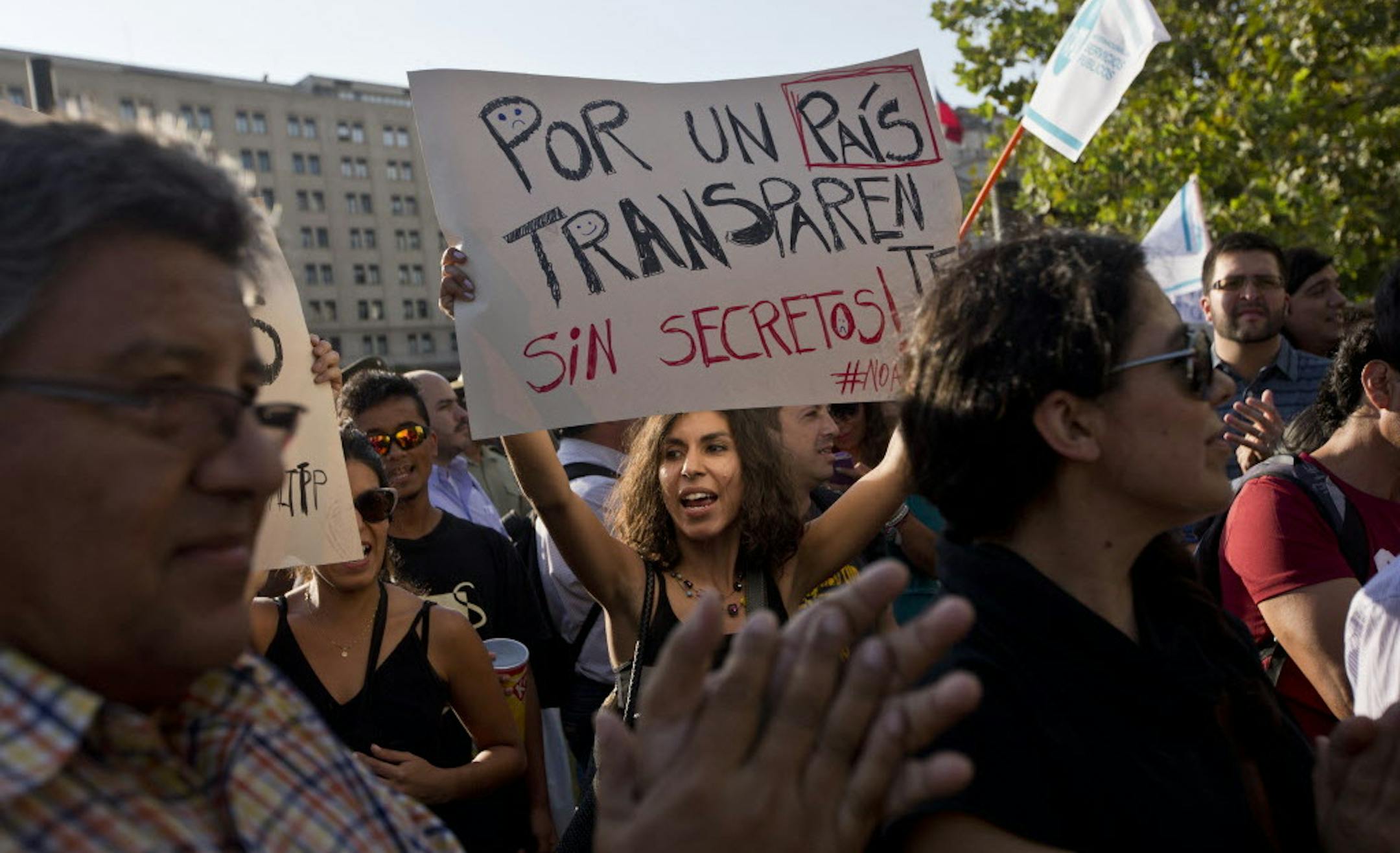 A woman holds a sign with a message that reads in Spanish; "For a transparent country, without secrets," during a demonstration against the signing of the global free-trade deal known as the Trans-Pacific Partnership, or TPP, outside La Moneda presidential palace, in Santiago, Chile, Thursday, Feb. 4, 2016. Protesters voiced their opposition to the signing of the 12-country pact that includes Chile, Peru and Mexico, because they say it will cost jobs and threaten national sovereignty. The deal w