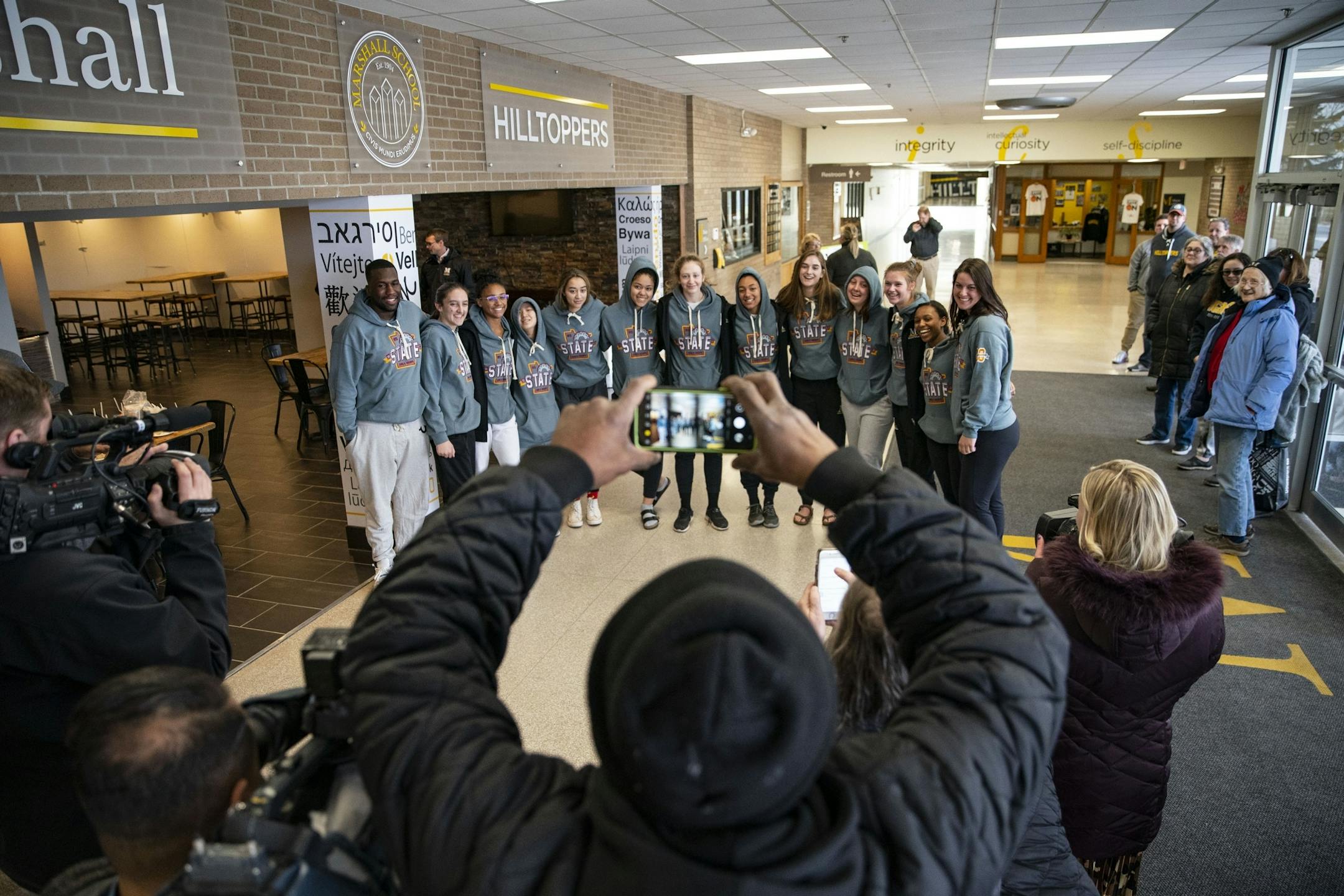 Parents and members of the local media took photos and video of the Duluth Marshall girl's basketball team after they returned home on Friday.
