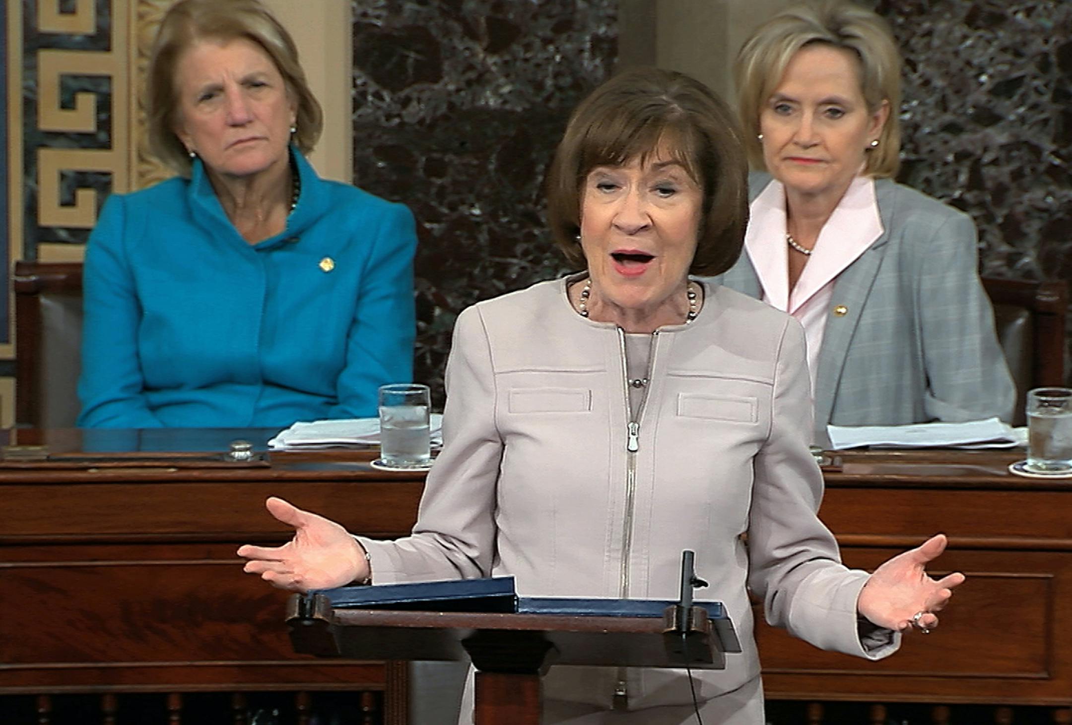 In this image from video provided by Senate TV, Sen. Susan Collins, R-Maine., speaks on the Senate floor about her vote on Supreme Court nominee Judge Brett Kananaugh, Friday, Oct. 5, 2018 in the Capitol in Washington. Sen Shelly Capito, R-W.Va., sits rear left and Sen. Cindy Hyde-Smith, R-Miss., sits right. (Senate TV via AP)