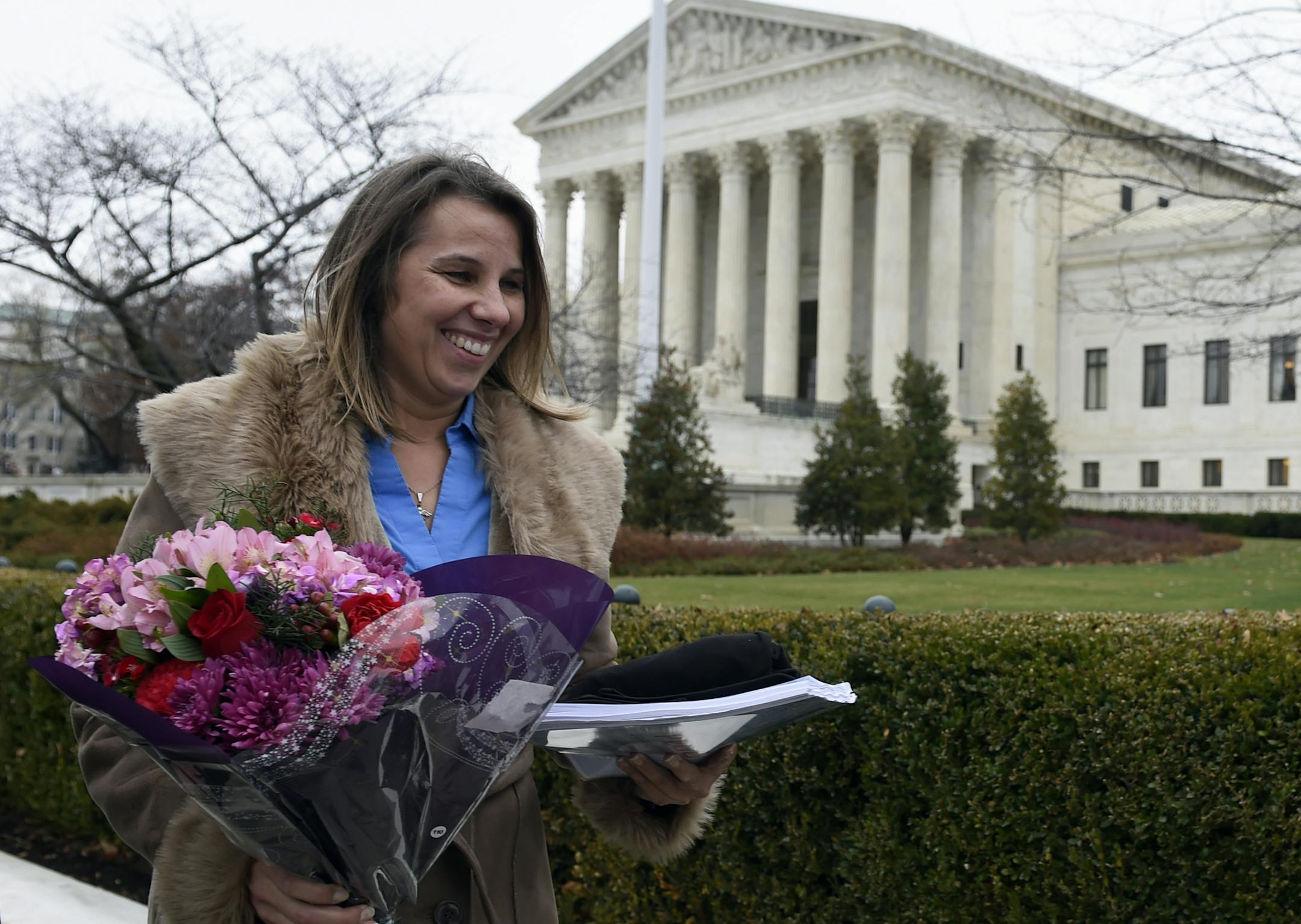 Peggy Young, a Virginia woman who lost her UPS job because she became pregnant, carries a bouquet of flowers as she leaves the Supreme Court in Washington, Wednesday, Dec. 3, 2014. The Supreme Court is weighing how much employers must do to accommodate pregnant workers under a federal law aimed at combating discrimination against them. (AP Photo/Susan Walsh)