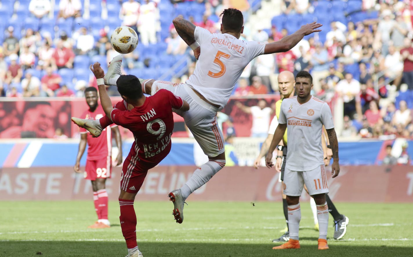 Atlanta United defender Leandro Gonzalez Pirez, center, jumps to kick the ball away from New York Red Bulls midfielder Andreas Ivan during the second half of an MLS soccer match, Sunday, Sept. 30, 2018, in Harrison, N.J. The New York Red Bulls won 2-0. (AP Photo/Steve Luciano)