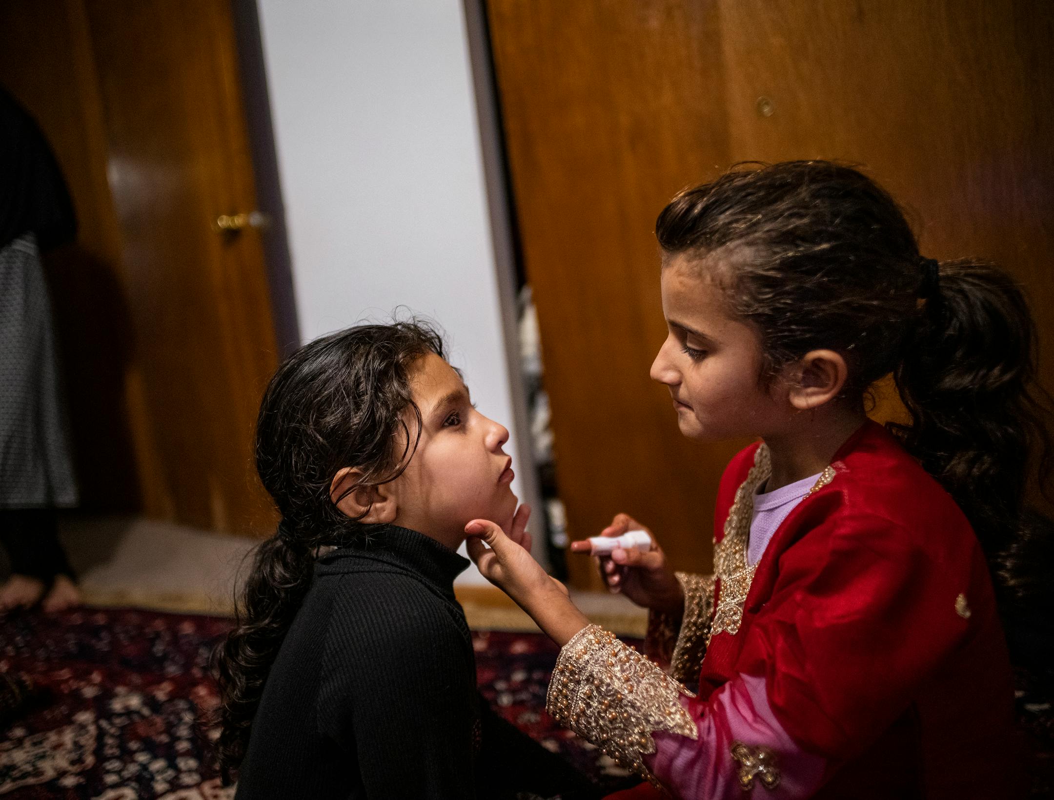 Asia Momand, right, puts lipstick on Maryam Mulakhail, as they play in Bloomington.