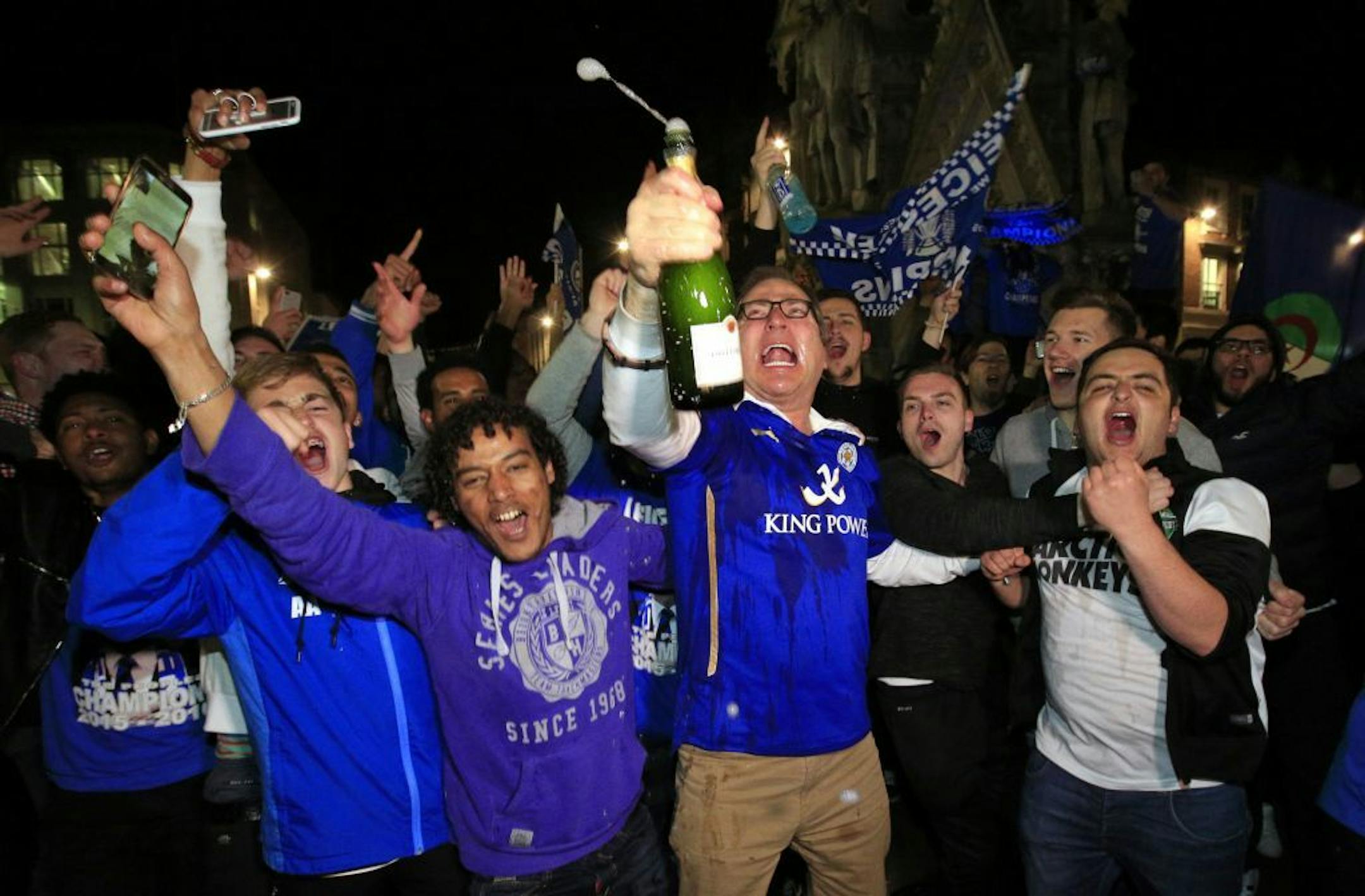 Leicester City fans celebrate at the clock tower in Leicester after seeing their side crowned English Premier League soccer champions following Tottenham Hotspur's 2-2 draw against Chelsea. The match resulted in Leicester City winning the Premier League, Monday May 2, 2016. (Joe Giddens/PA via AP) UNITED KINGDOM OUT NO SALES NO ARCHIVE