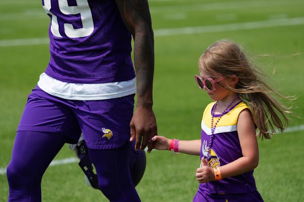 A young Vikings fan walked with cornerback Chandon Sullivan (39) as he took the field for training camp.