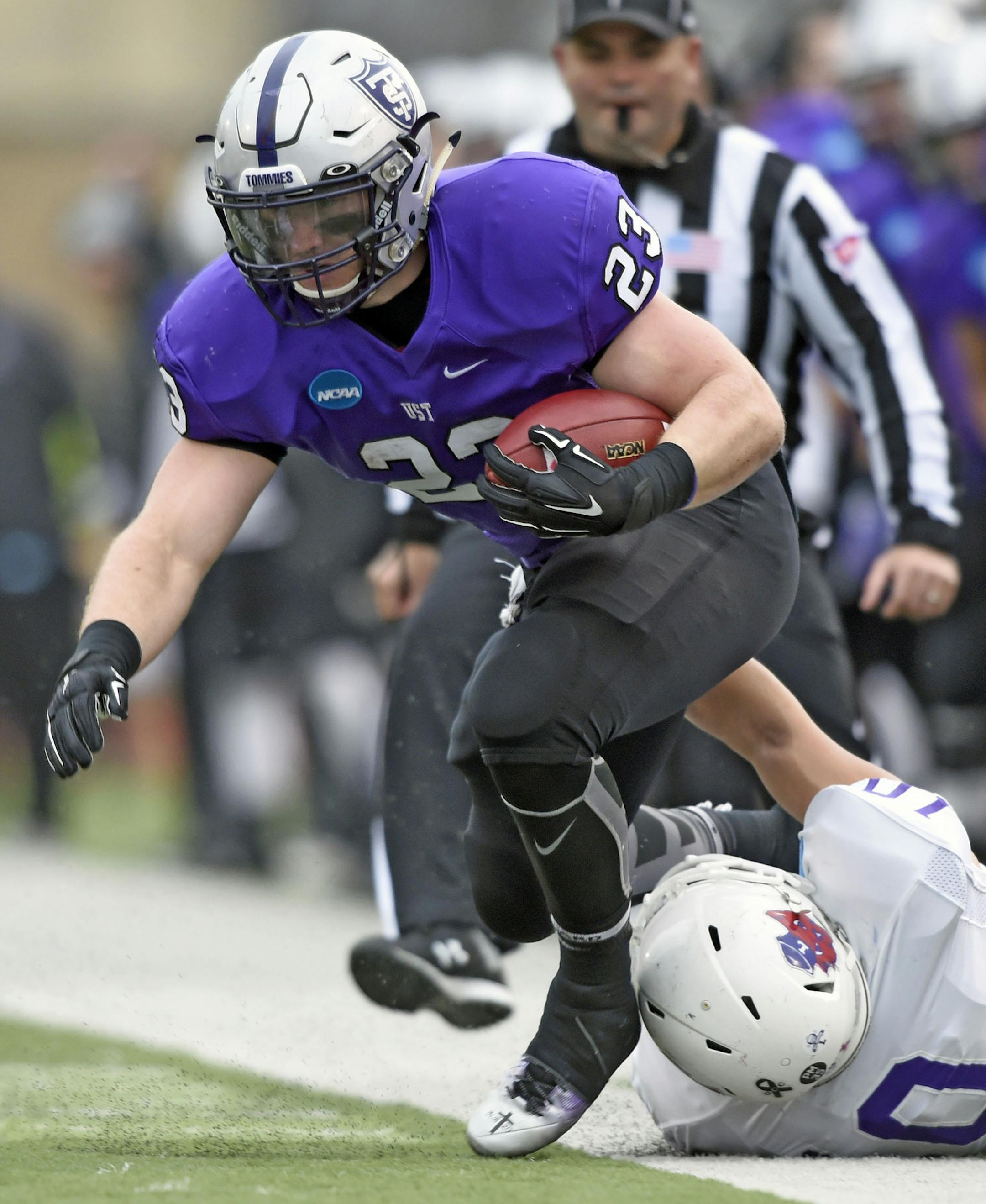 Linfield middle linebacker Skylor Elgarico (10) pulls St. Thomas running back Jordan Roberts (23) out of bounds during the first quarter during a Division III NCAA college football semifinal game on Saturday, Dec. 12, 2015, in St. Paul, Minn. (AP Photo/Hannah Foslien)