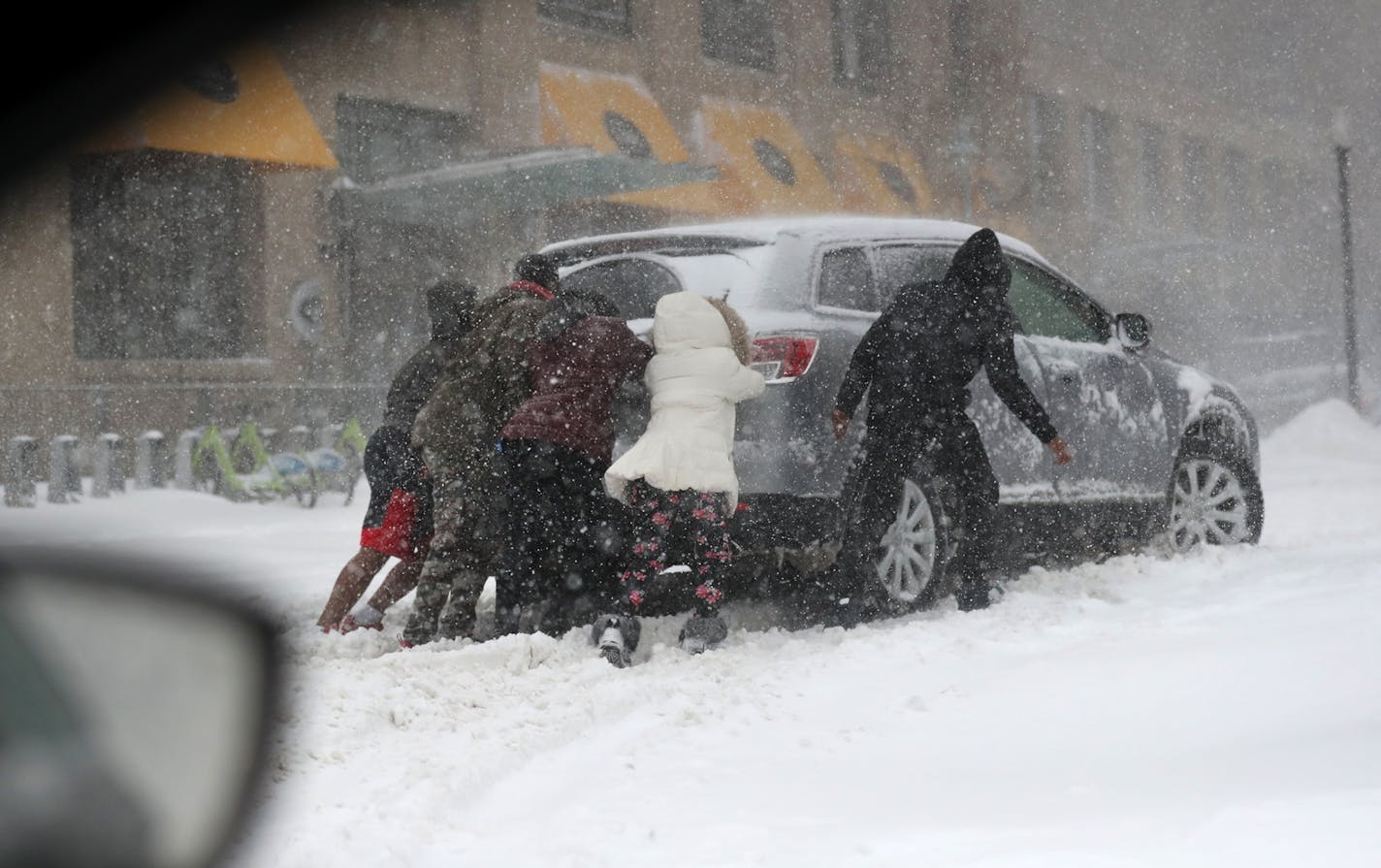 A car is stuck on 10th Avenue near E. Lake St. in a blizzard Saturday, April 14, 2018, in Minneapolis, MN.