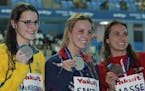 Gold medalist Regan Smith, center, stands with silver medalist Kaylee McKeown, left, of Australia and bronze medalist Kylie Masse of Canada.