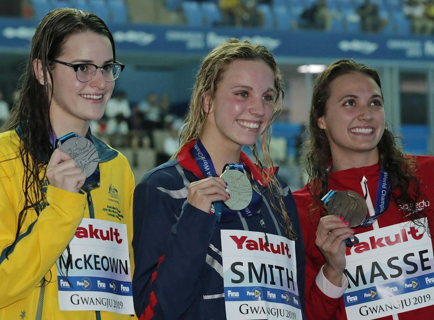 Gold medalist Regan Smith, center, stands with silver medalist Kaylee McKeown, left, of Australia and bronze medalist Kylie Masse of Canada.