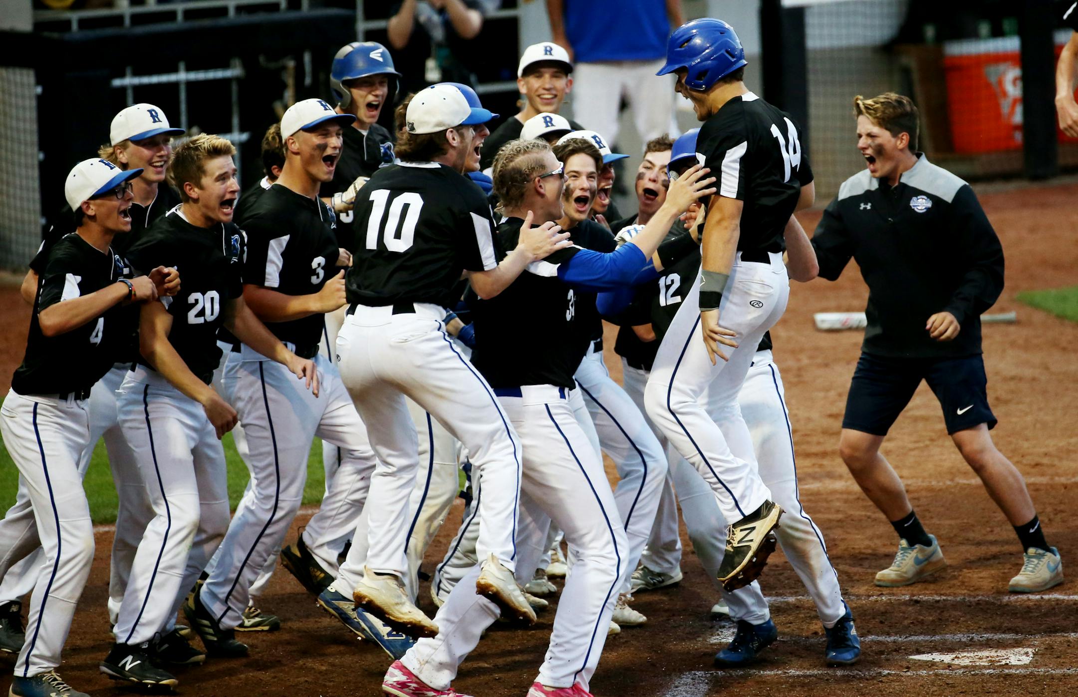 Rogers first baseman Aaron Schmidt (14) jumps into his team at home base after hitting a home run in the first inning. ] NICOLE NERI • nicole.neri@startribune.com BACKGROUND INFORMATION: Hopkins vs. Rogers in the Class 4A baseball state quarterfinals Friday, June 14, 2019