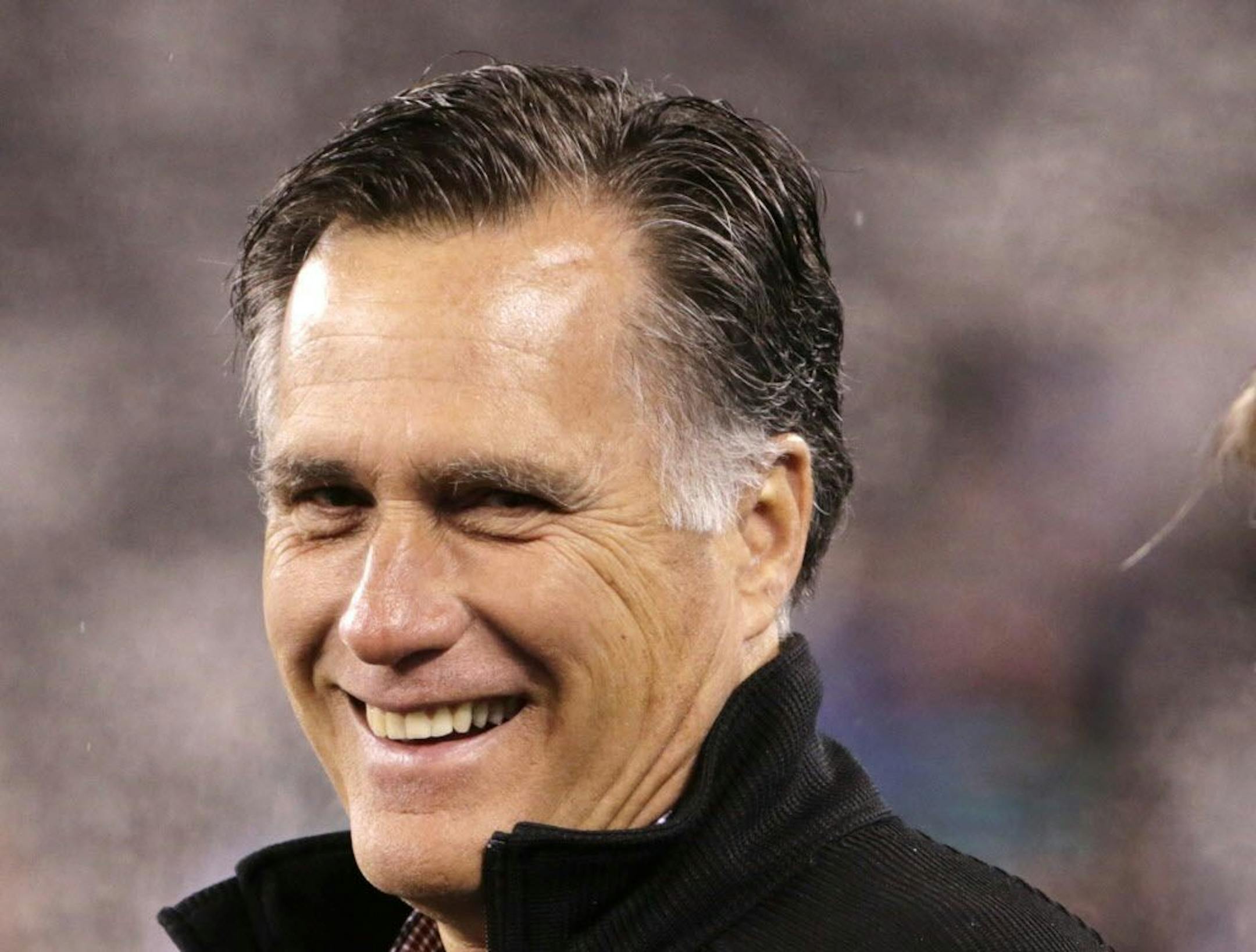 In this photo taken Dec. 1, 2014. for Republican presidential canadiate Mitt Romney smiles on the field before an NFL football game between the New York Jets and the Miami Dolphins in East Rutherford, N.J.
